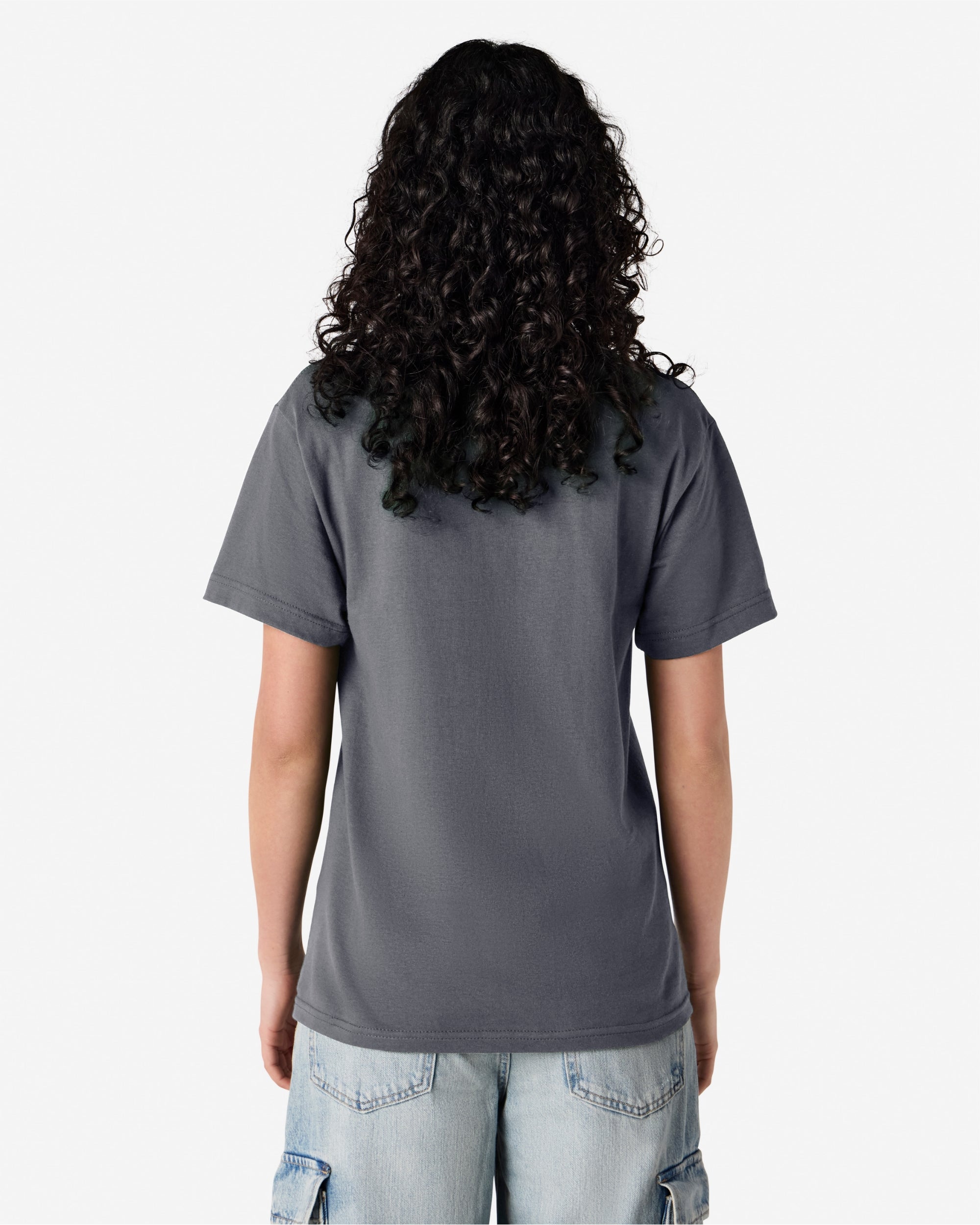 Female Model wearing a Charcoal Heavyweight Unisex Short Sleeve Crew Neck Tee, paired with blue jeans, standing against a plain background (back pose) -charcoal