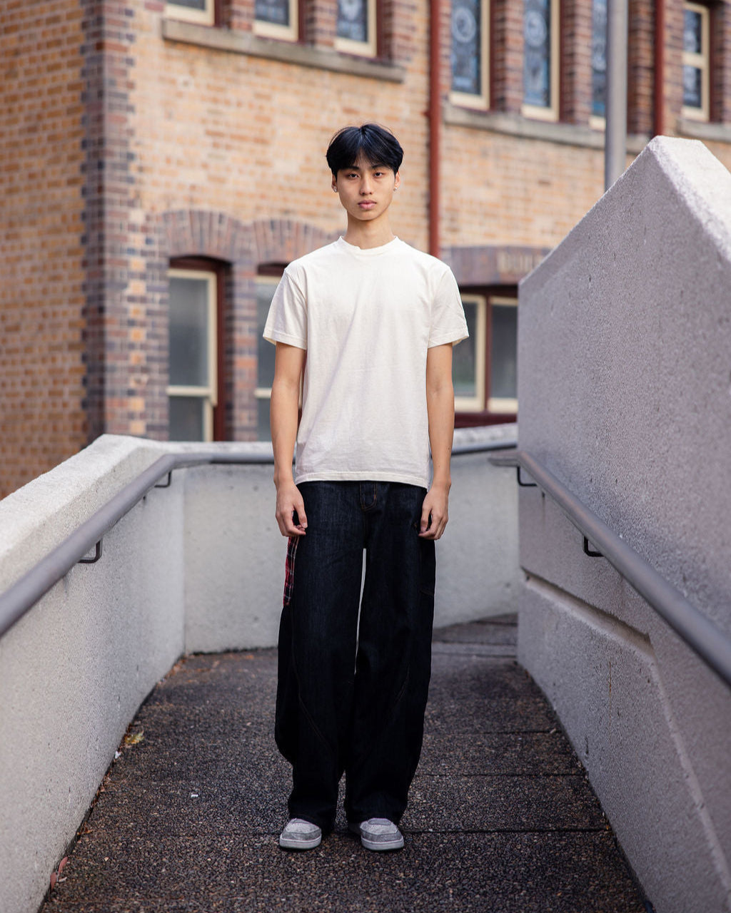 Male Model wearing a Cream Heavyweight Unisex Short Sleeve Crew Neck Tee, paired with blue jeans, standing against a plain background (front pose) -Cream