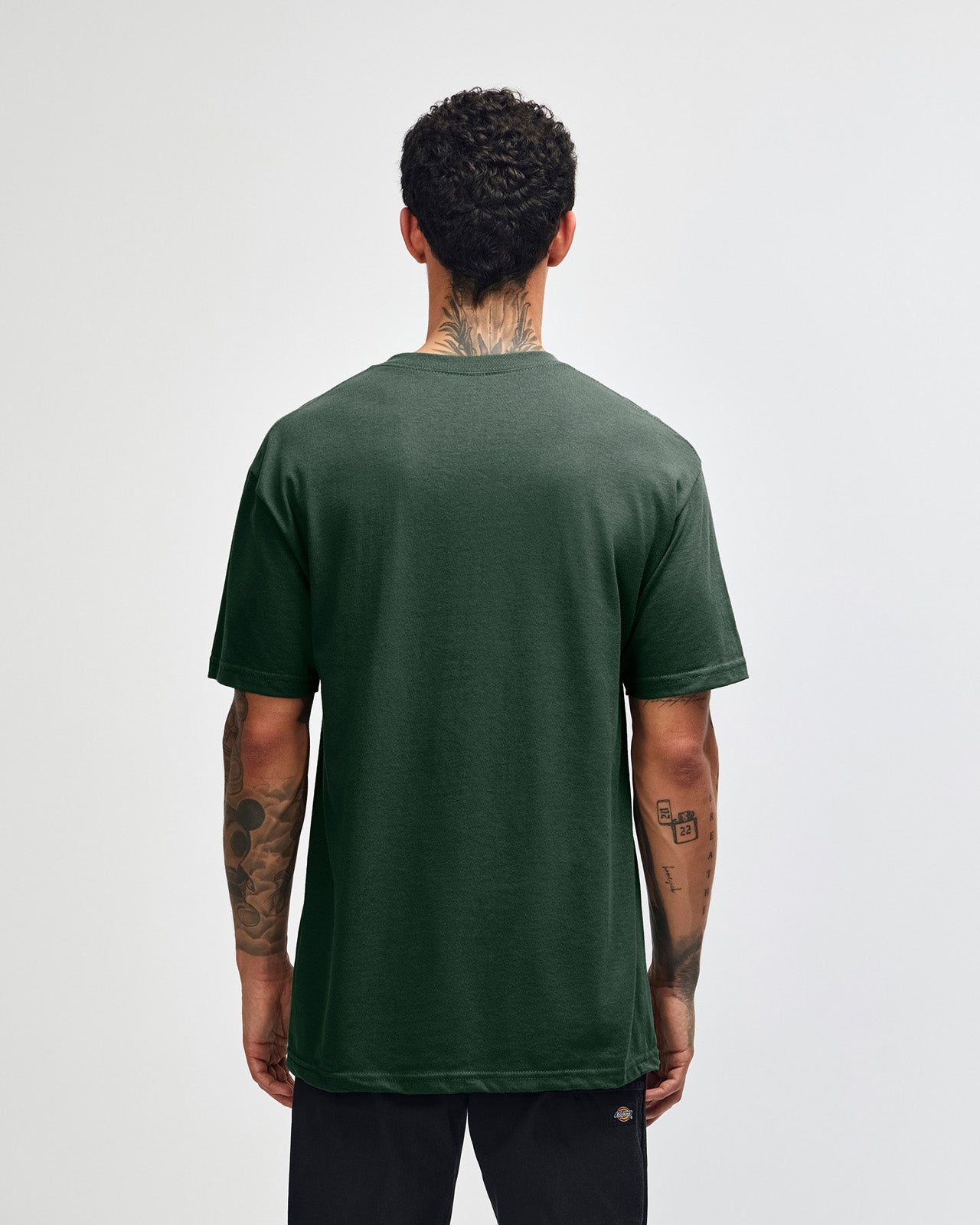 Male Model wearing a Forest Heavyweight Unisex Short Sleeve Crew Neck Tee, paired with blue jeans, standing against a plain background (front pose) -forest green