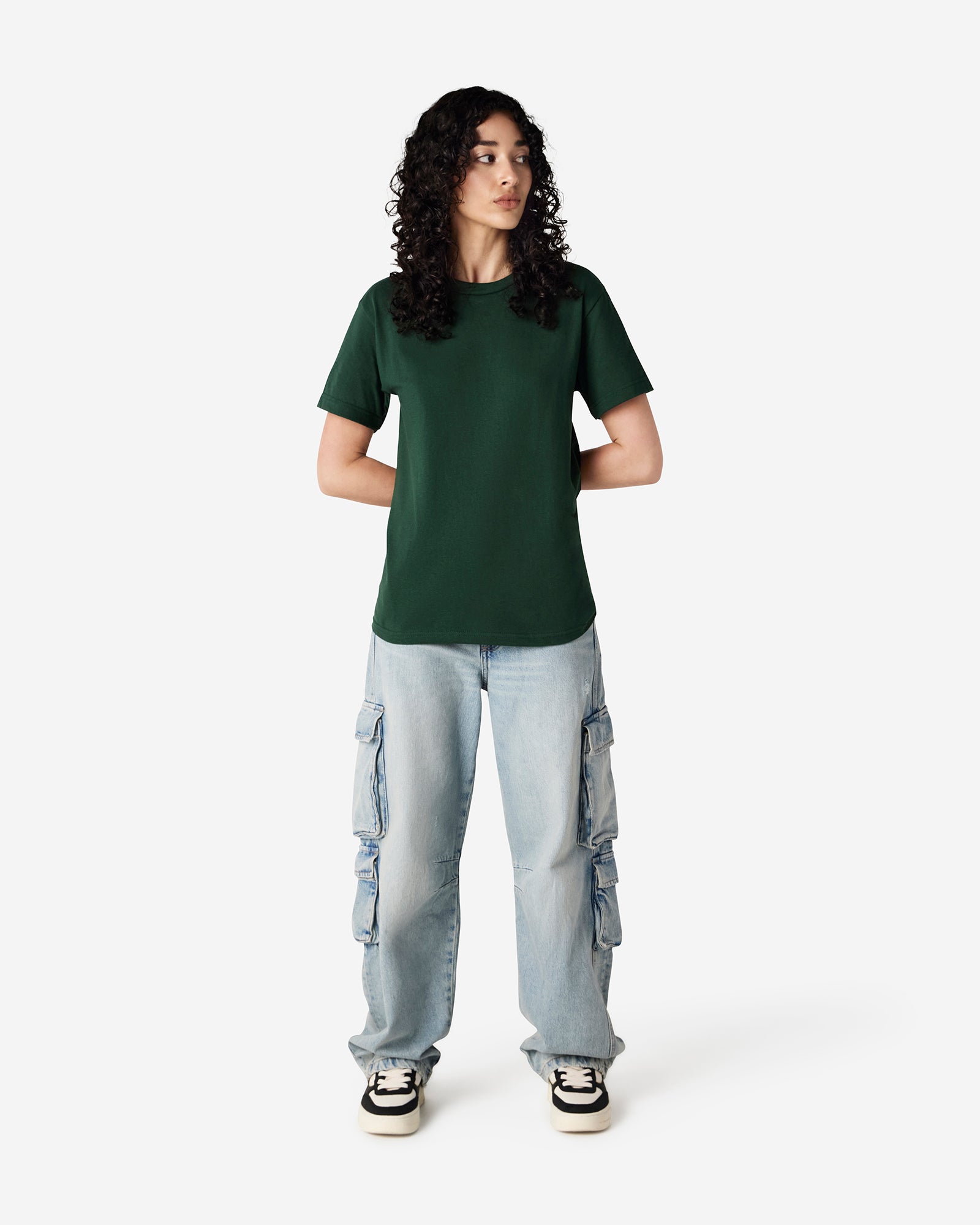 Female Model wearing a forest green Heavyweight Unisex Short Sleeve Crew Neck Tee, paired with blue jeans, standing against a plain background (front pose) -forest green