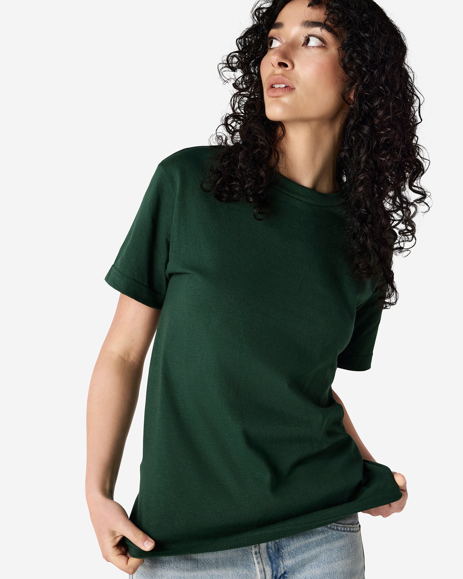 Female Model wearing a Forest Heavyweight Unisex Short Sleeve Crew Neck Tee, paired with blue jeans, standing against a plain background (front pose) -forest green