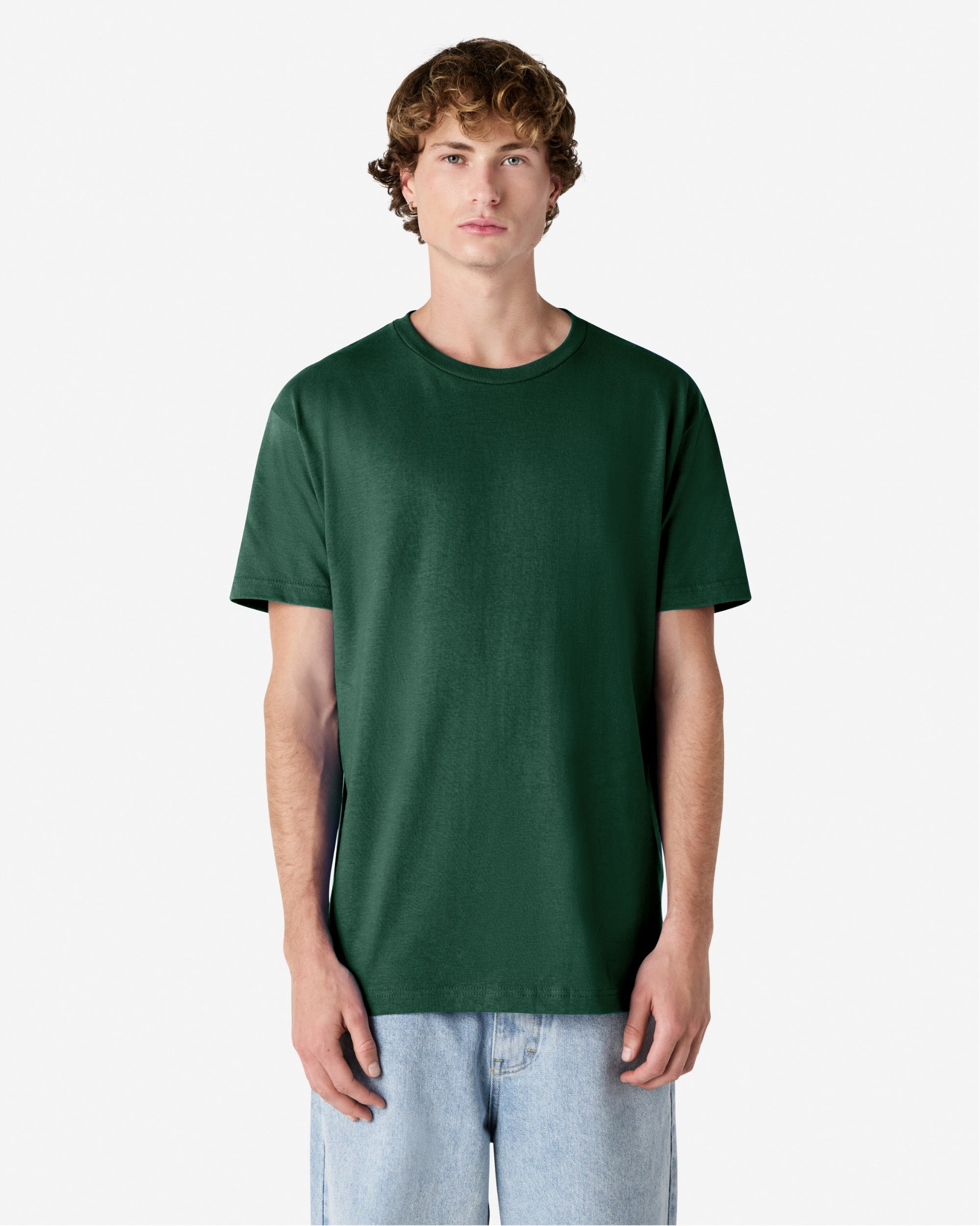 Male Model wearing a Forest Heavyweight Unisex Short Sleeve Crew Neck Tee, paired with blue jeans, standing against a plain background (front pose) -forest green