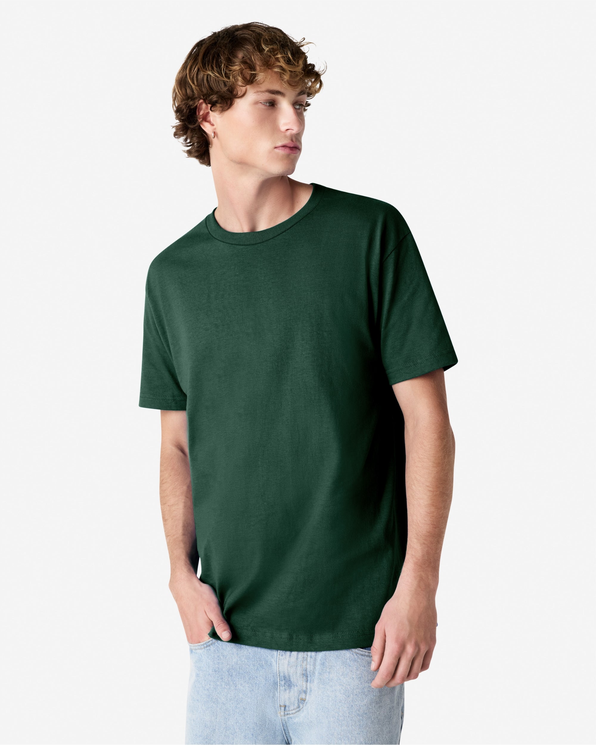 Male Model wearing a Forest Heavyweight Unisex Short Sleeve Crew Neck Tee, paired with blue jeans, standing against a plain background (front pose) -forest green