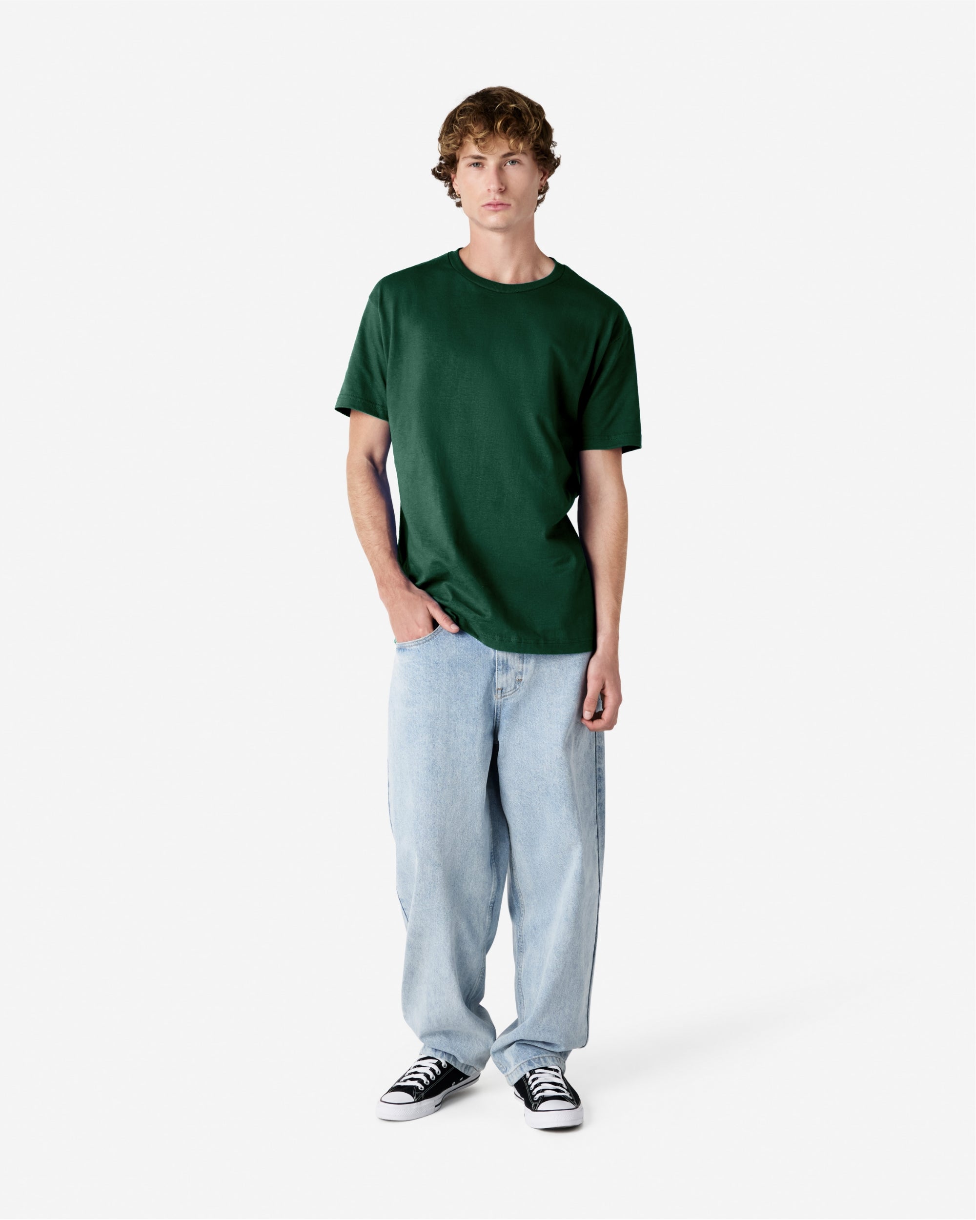 Male Model wearing a Forest Heavyweight Unisex Short Sleeve Crew Neck Tee, paired with blue jeans, standing against a plain background (front pose) -forest green