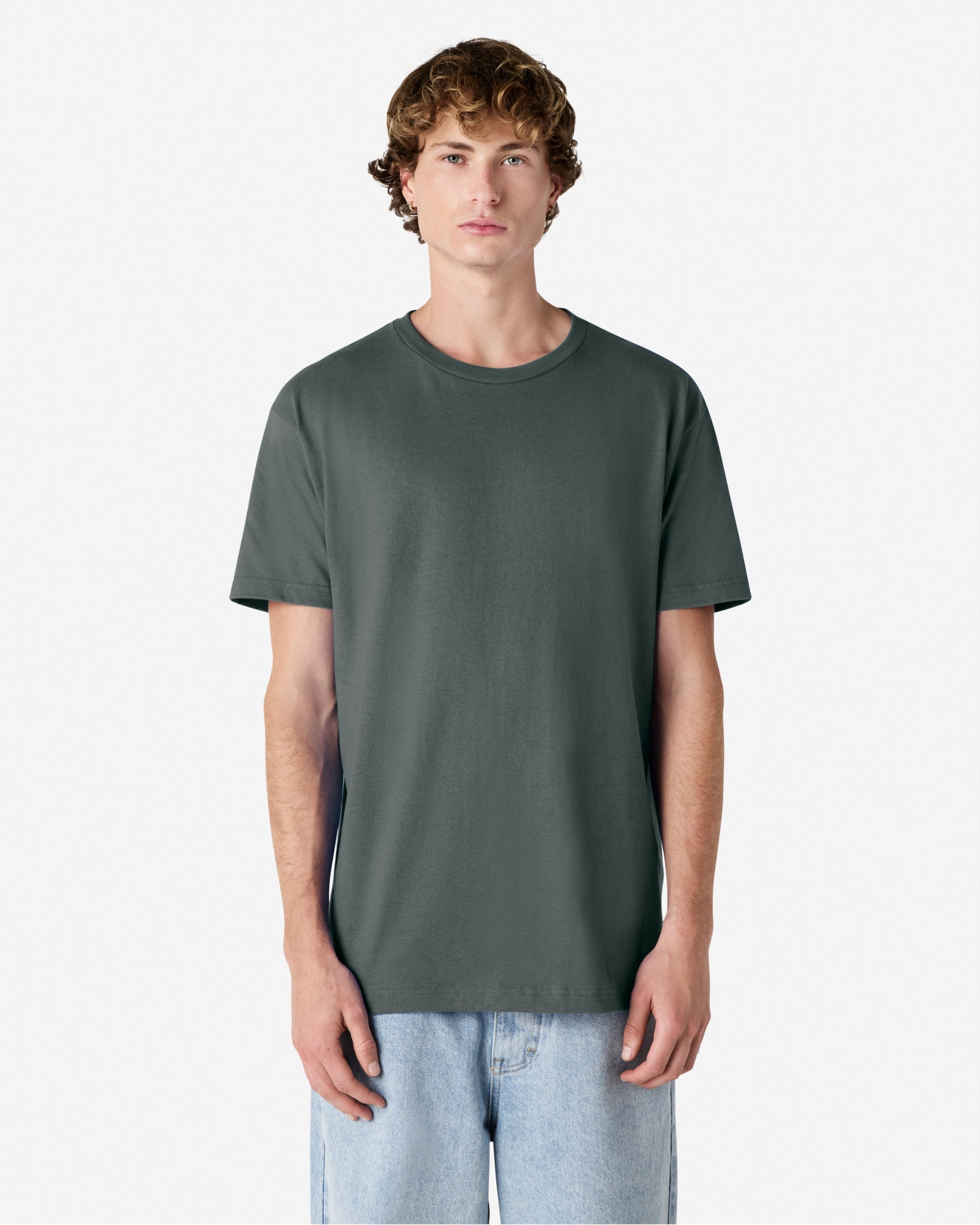 Male Model wearing a Heather Charcoal Heavyweight Unisex Short Sleeve Crew Neck Tee, paired with blue jeans, standing against a plain background (front pose) -heather charcoal