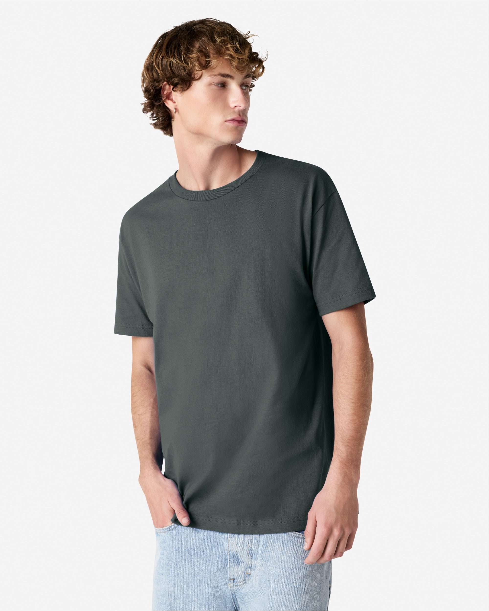 Male Model wearing a Heather Charcoal Heavyweight Unisex Short Sleeve Crew Neck Tee, paired with blue jeans, standing against a plain background (front pose) -heather charcoal