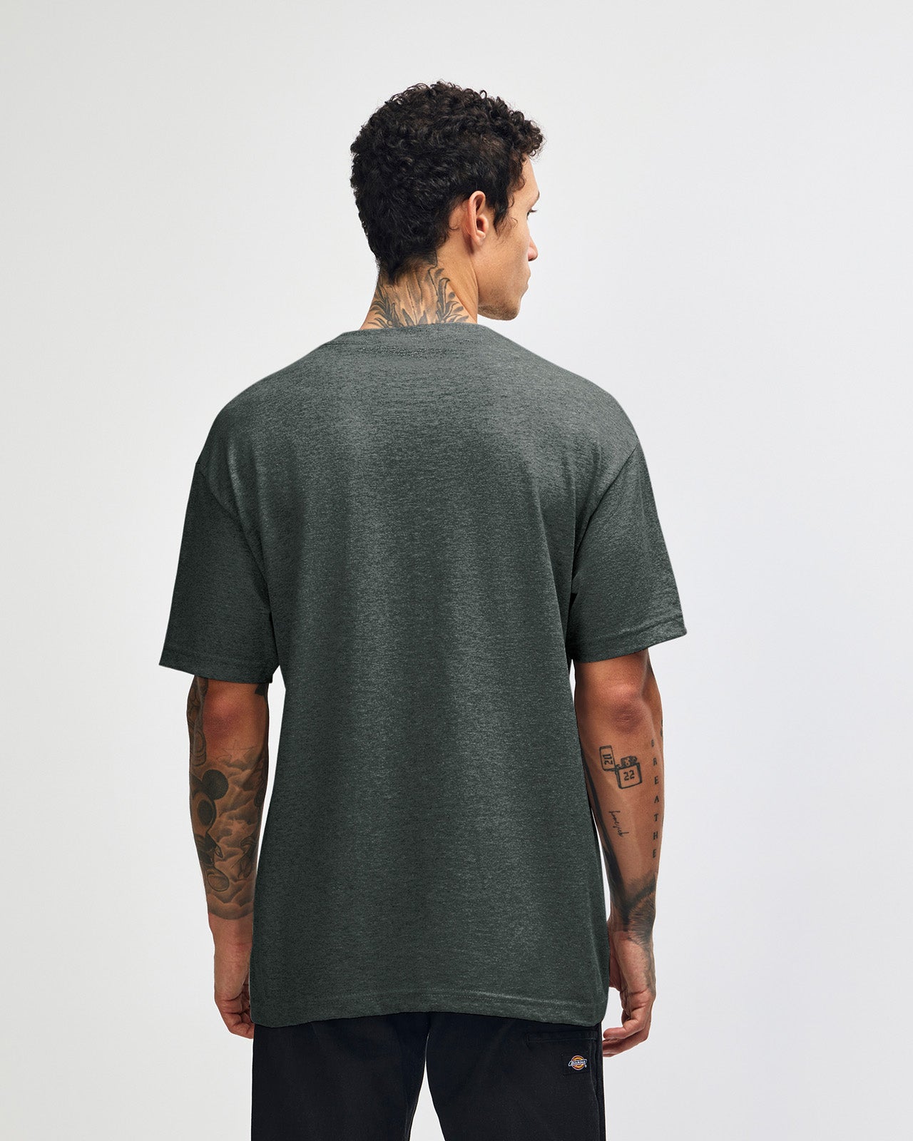 Male Model wearing a Heather Charcoal Heavyweight Unisex Short Sleeve Crew Neck Tee, paired with blue jeans, standing against a plain background (front pose) -heather charcoal