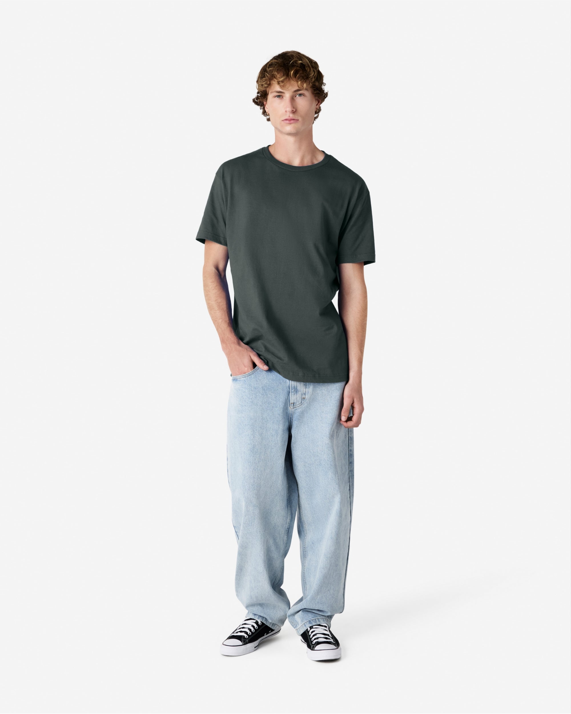 Male Model wearing a Heather Charcoal Heavyweight Unisex Short Sleeve Crew Neck Tee, paired with blue jeans, standing against a plain background (front pose) -heather charcoal