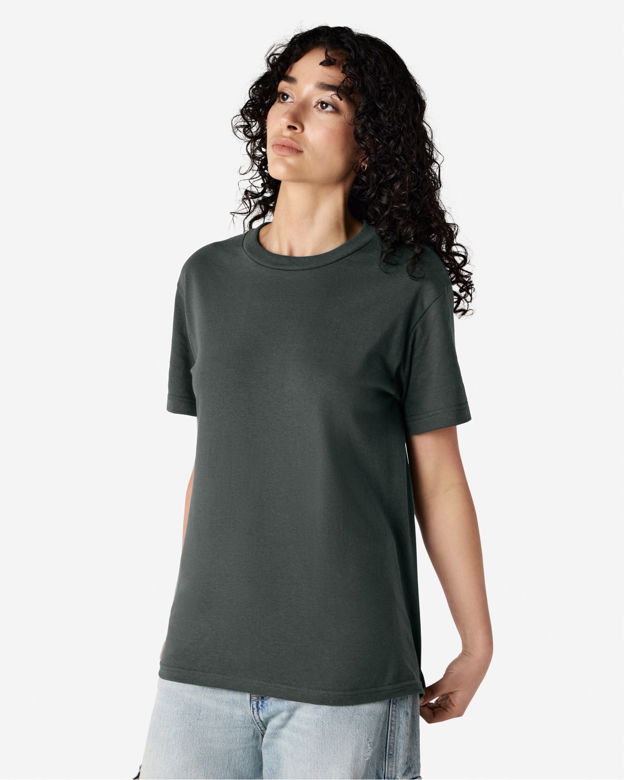 Female Model wearing a Heather Charcoal Heavyweight Unisex Short Sleeve Crew Neck Tee, paired with blue jeans, standing against a plain background (front pose) -heather charcoal