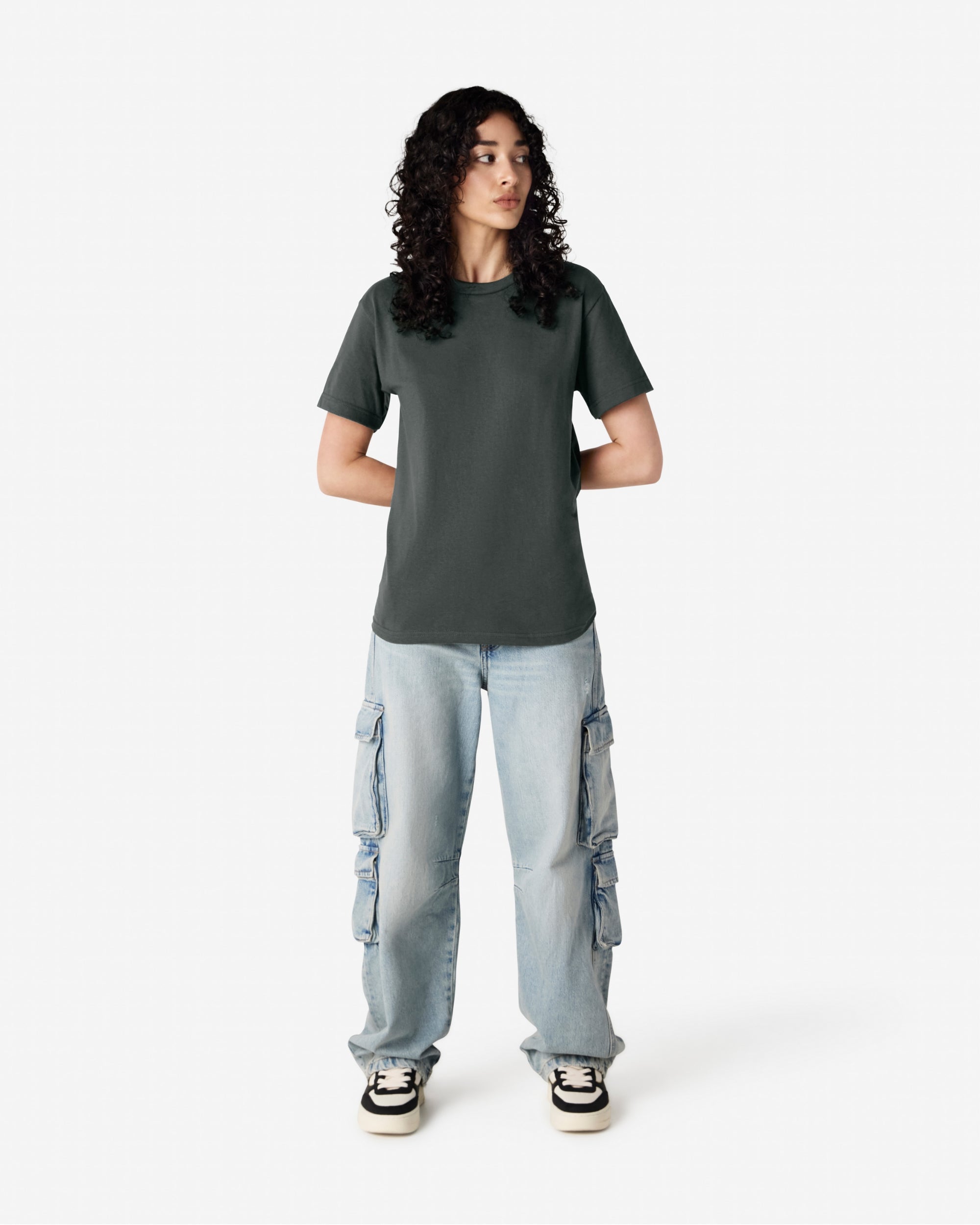 Female Model wearing a Heather Charcoal Heavyweight Unisex Short Sleeve Crew Neck Tee, paired with blue jeans, standing against a plain background (front pose) -heather charcoal