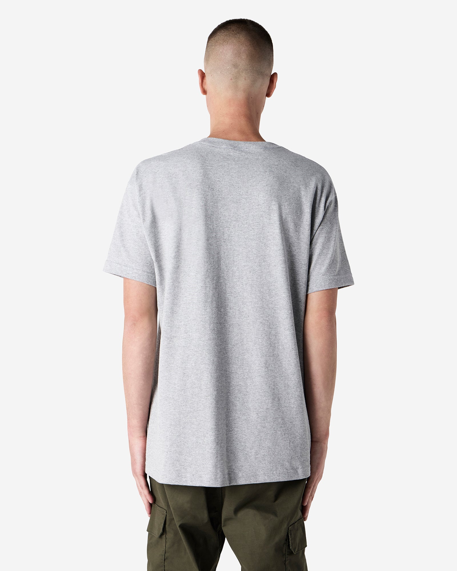 Male Model wearing a Heather Grey Heavyweight Unisex Short Sleeve Crew Neck Tee, paired with blue jeans, standing against a plain background (back pose) -heather grey