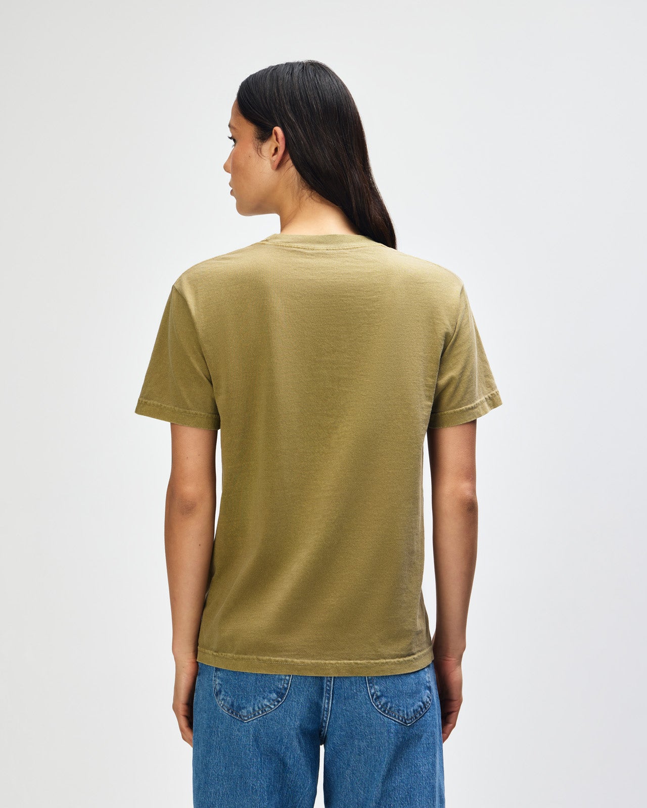 Female Model wearing a Military Green Heavyweight Unisex Short Sleeve Crew Neck Tee, paired with blue jeans, standing against a plain background (front pose) -military green