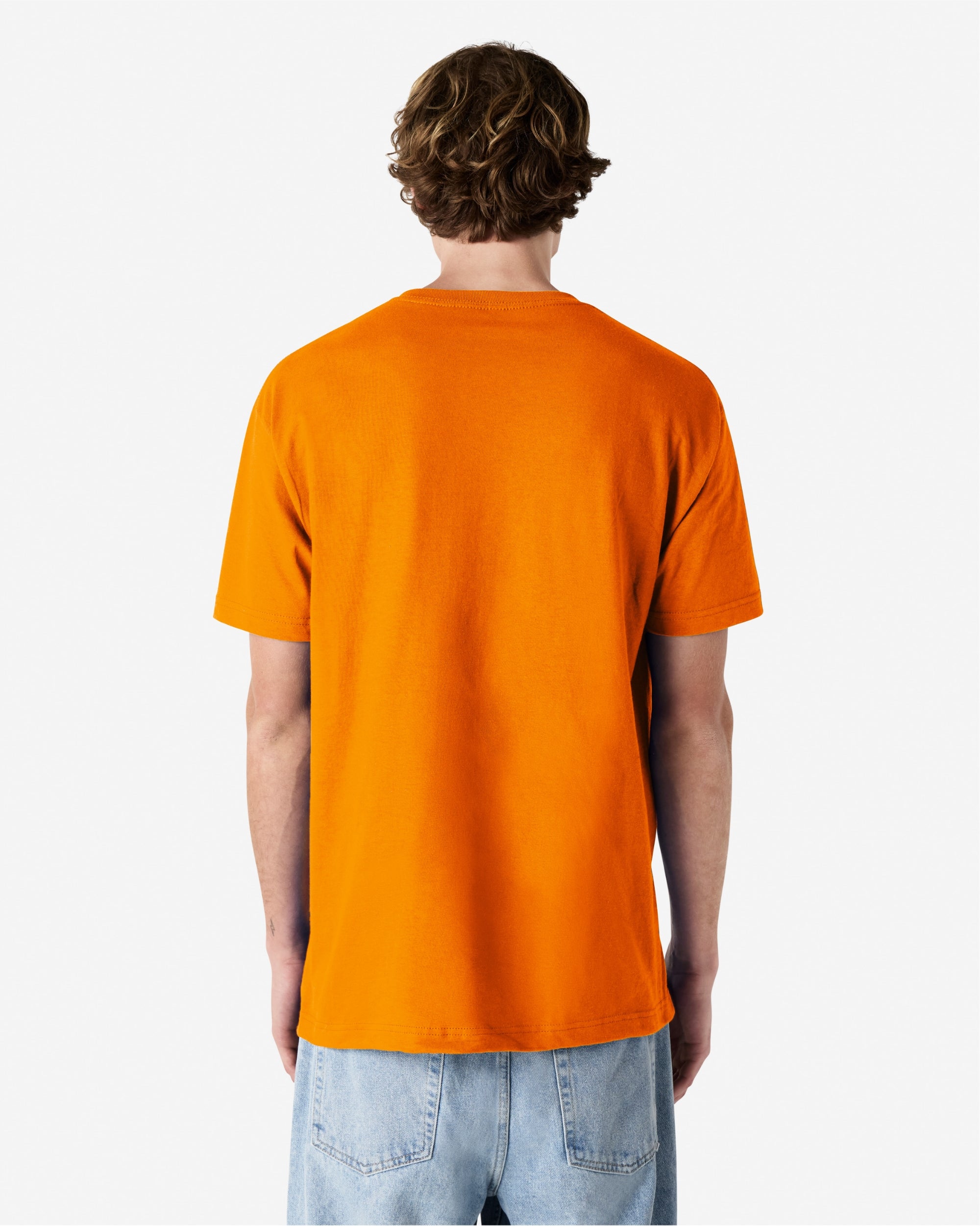 Male Model wearing a Orange Heavyweight Unisex Short Sleeve Crew Neck Tee, paired with blue jeans, standing against a plain background (back pose) -orange