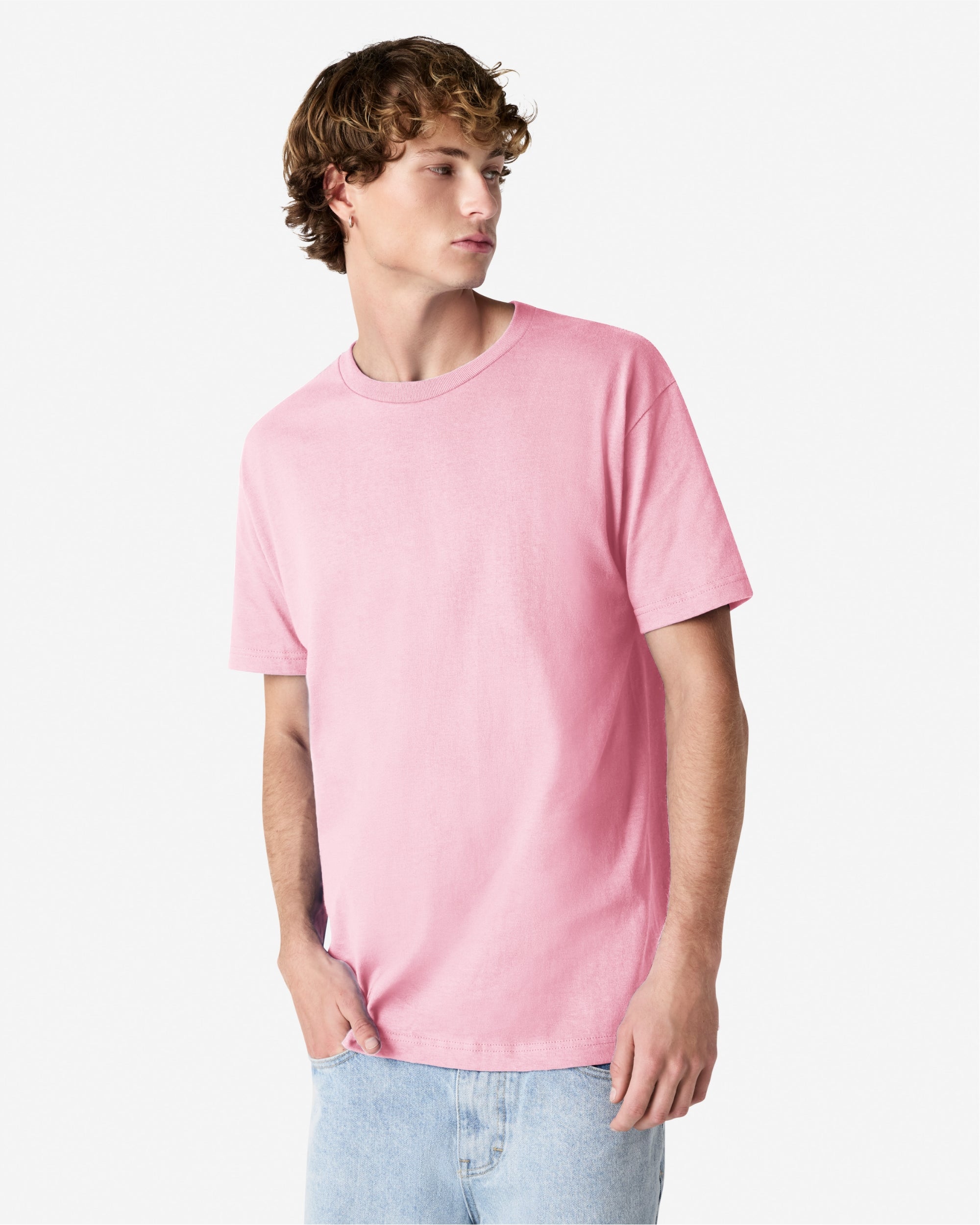 Male Model wearing a pink Heavyweight Unisex Short Sleeve Crew Neck Tee, paired with blue jeans, standing against a plain background (front pose) -pink