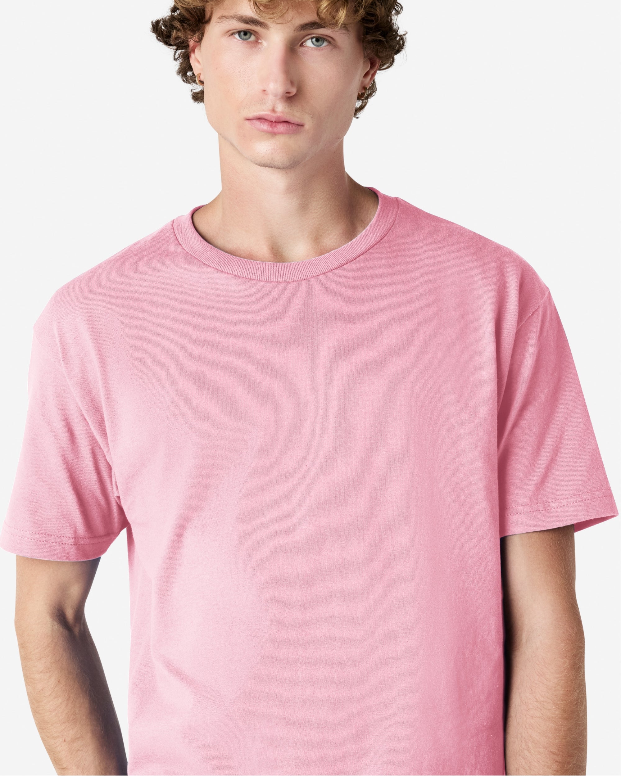 Male Model wearing a Pink Heavyweight Unisex Short Sleeve Crew Neck Tee, paired with blue jeans, standing against a plain background (front pose) -pink