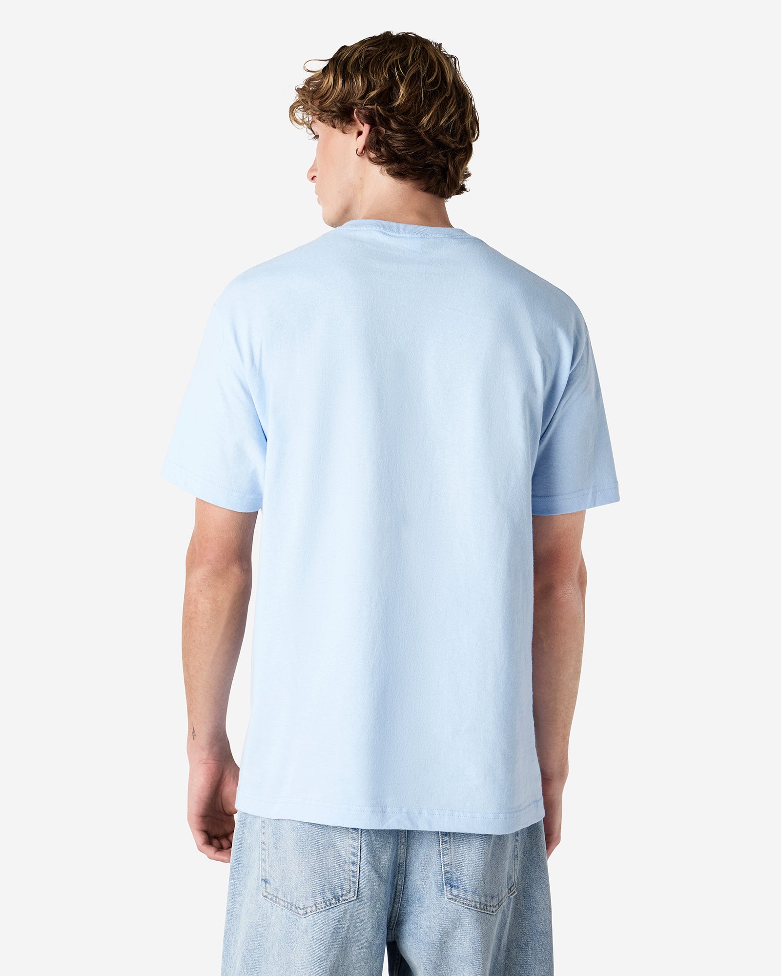 Male Model wearing a Powder Blue Heavyweight Unisex Short Sleeve Crew Neck Tee, paired with blue jeans, standing against a plain background (front pose) -powder blue
