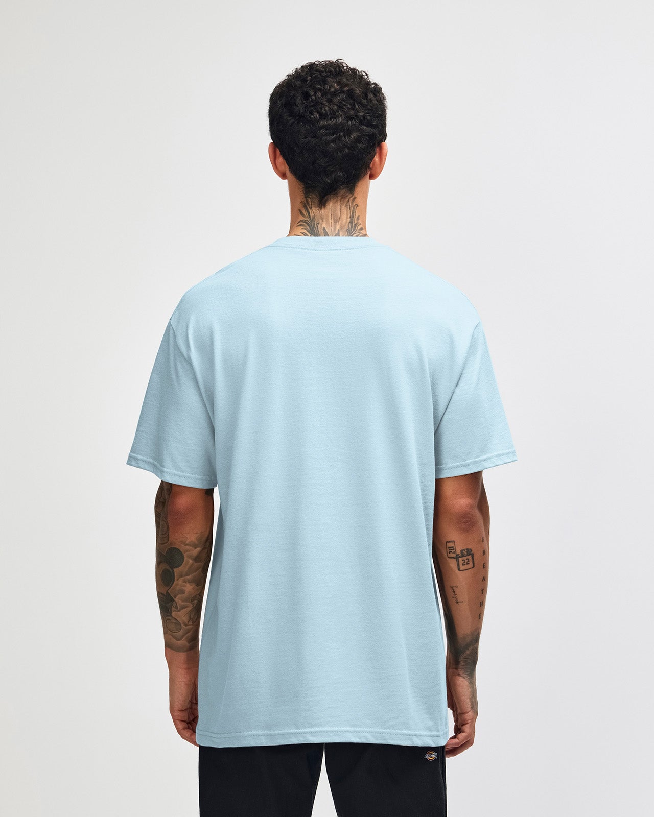 Male Model wearing a Powder Blue Heavyweight Unisex Short Sleeve Crew Neck Tee, paired with blue jeans, standing against a plain background (front pose) -powder blue