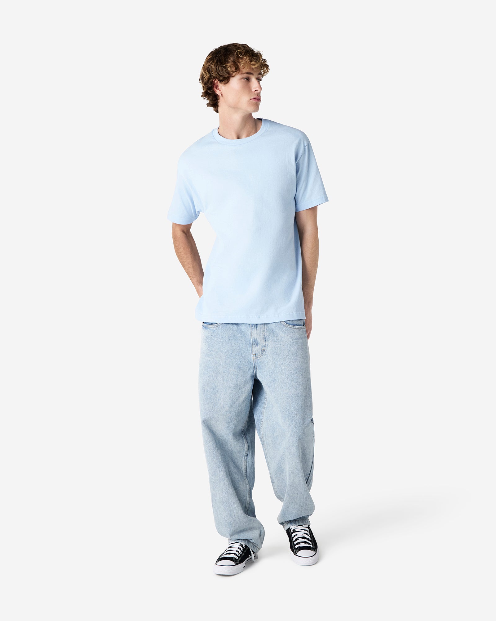 Male Model wearing a Powder Blue Heavyweight Unisex Short Sleeve Crew Neck Tee, paired with blue jeans, standing against a plain background (front pose) -powder blue