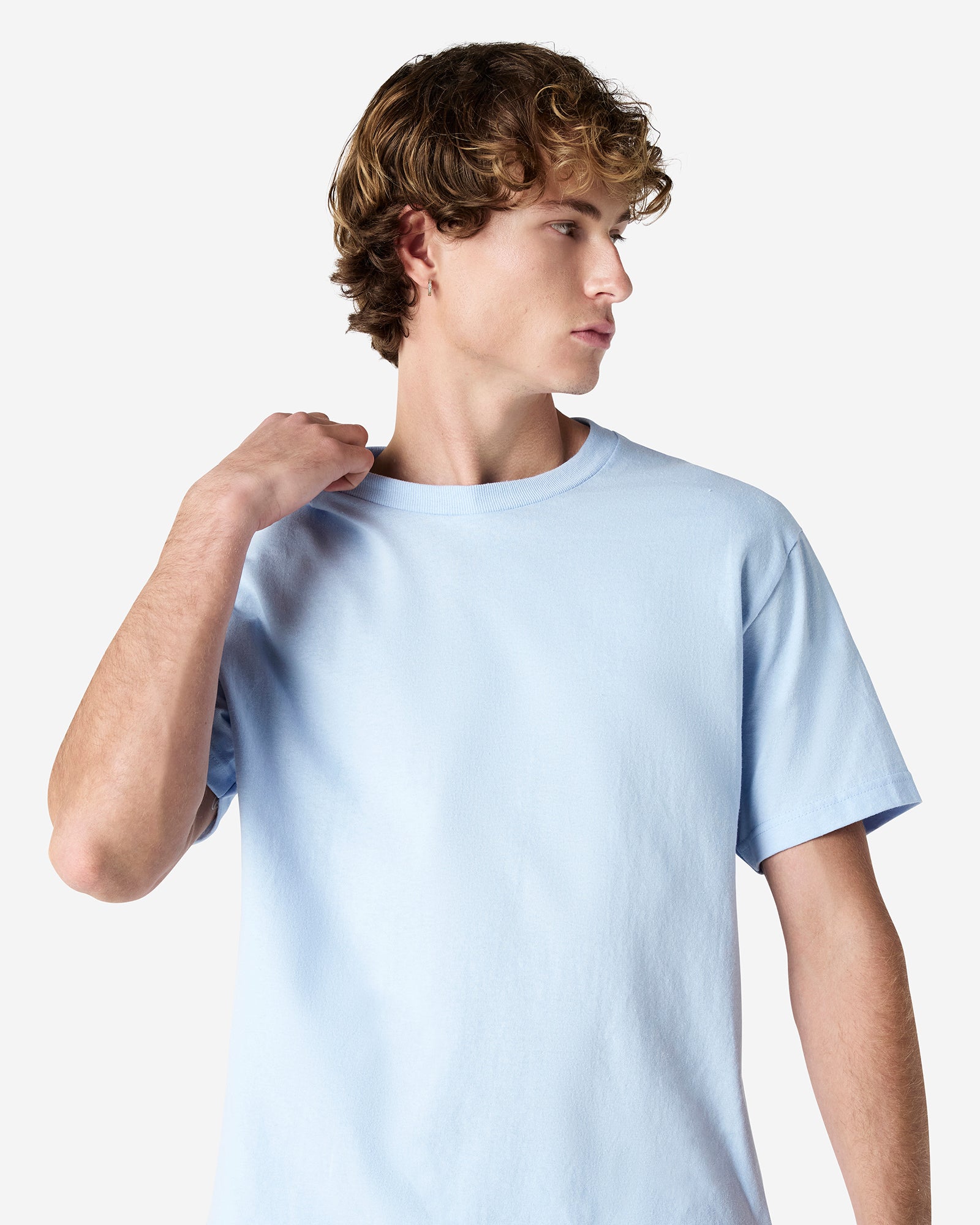 Male Model wearing a Powder Blue Heavyweight Unisex Short Sleeve Crew Neck Tee, paired with blue jeans, standing against a plain background (front pose) -powder blue