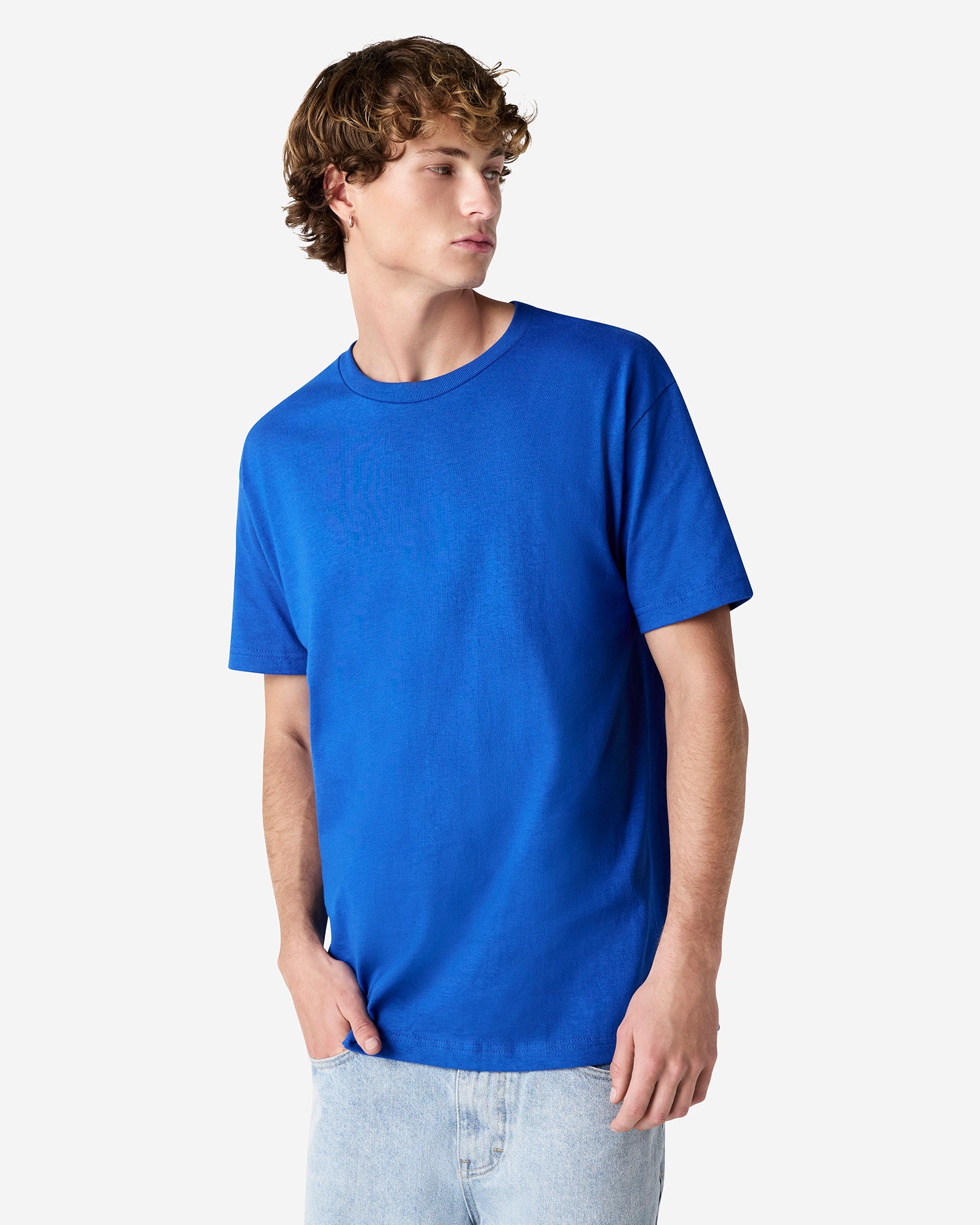 Male Model wearing a Royal Heavyweight Unisex Short Sleeve Crew Neck Tee, paired with blue jeans, standing against a plain background (front pose) -royal