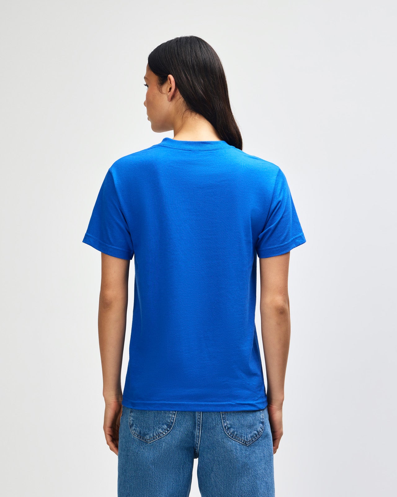 Female Model wearing a red Heavyweight Unisex Short Sleeve Crew Neck Tee, paired with blue jeans, standing against a plain background (front pose) -royal