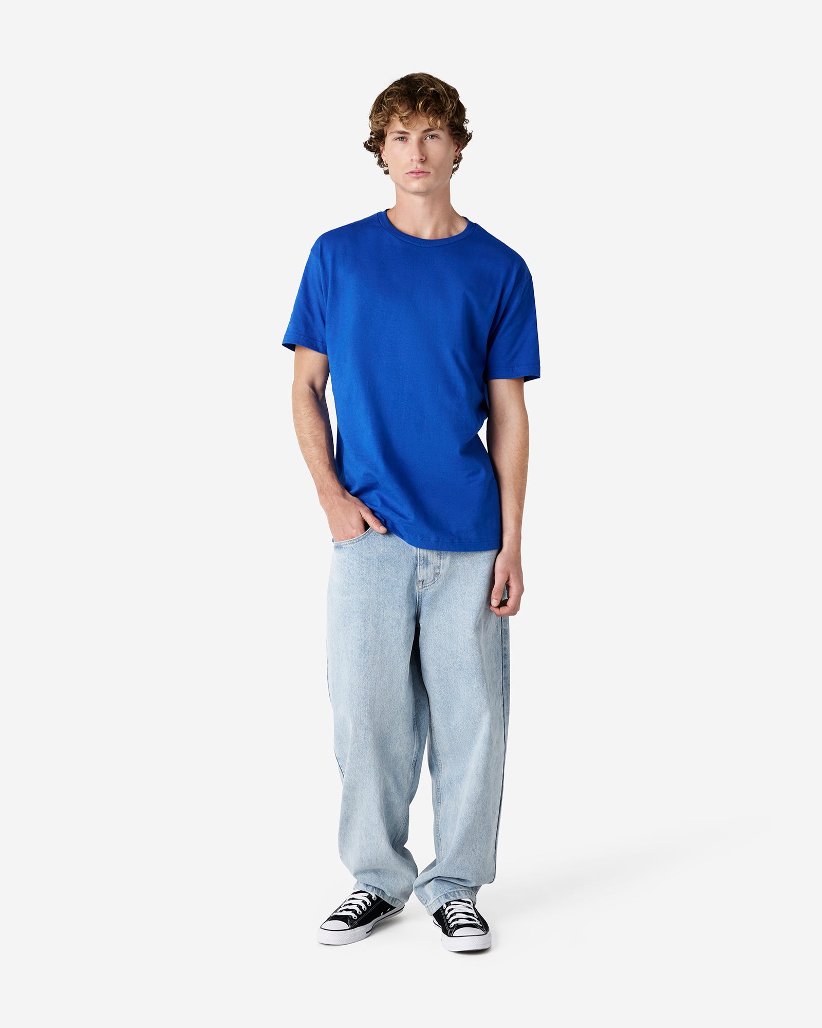 Male Model wearing a Royal Heavyweight Unisex Short Sleeve Crew Neck Tee, paired with blue jeans, standing against a plain background (front pose) -royal