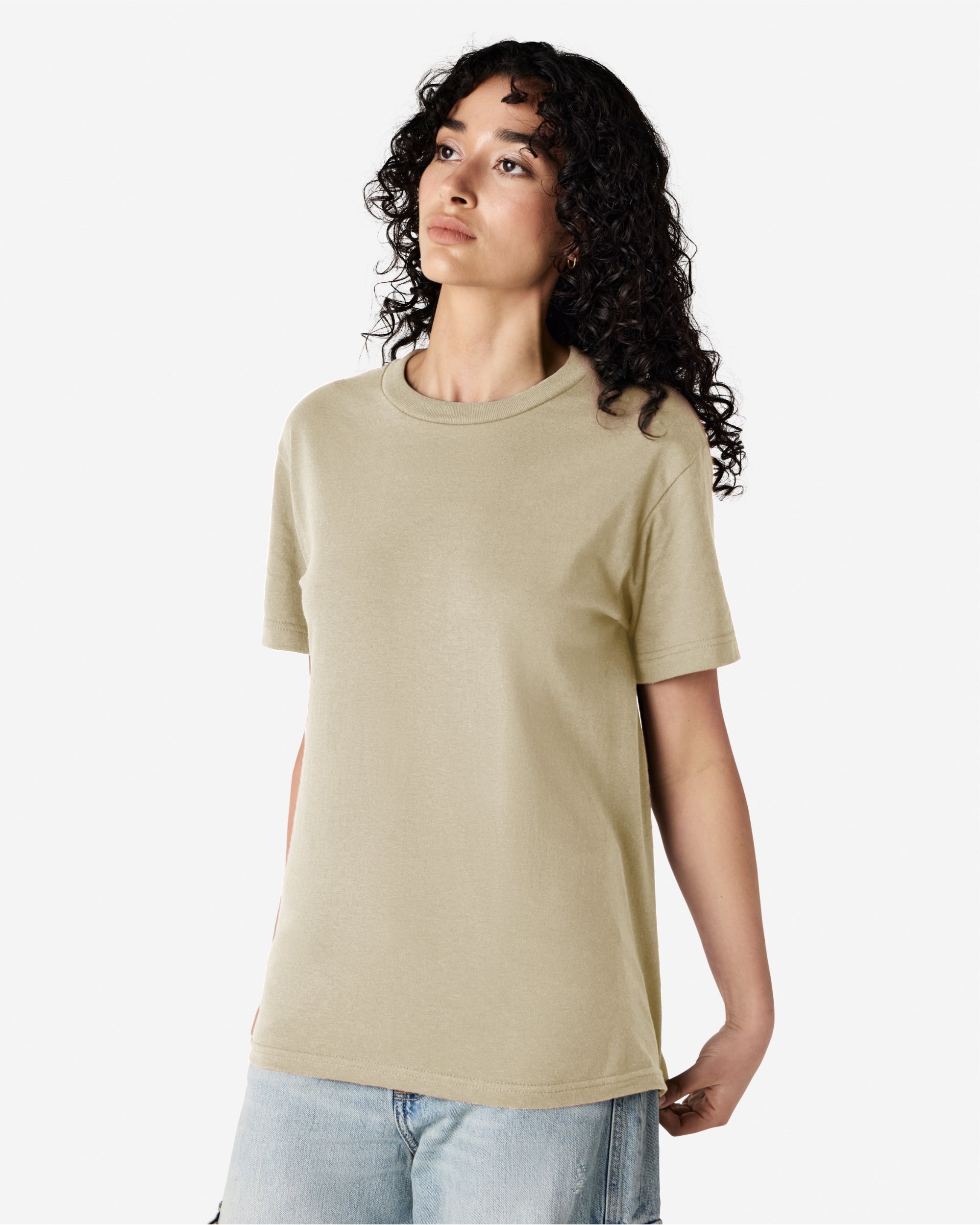 Female Model wearing a Sand Heavyweight Unisex Short Sleeve Crew Neck Tee, paired with blue jeans, standing against a plain background (front pose) -sand