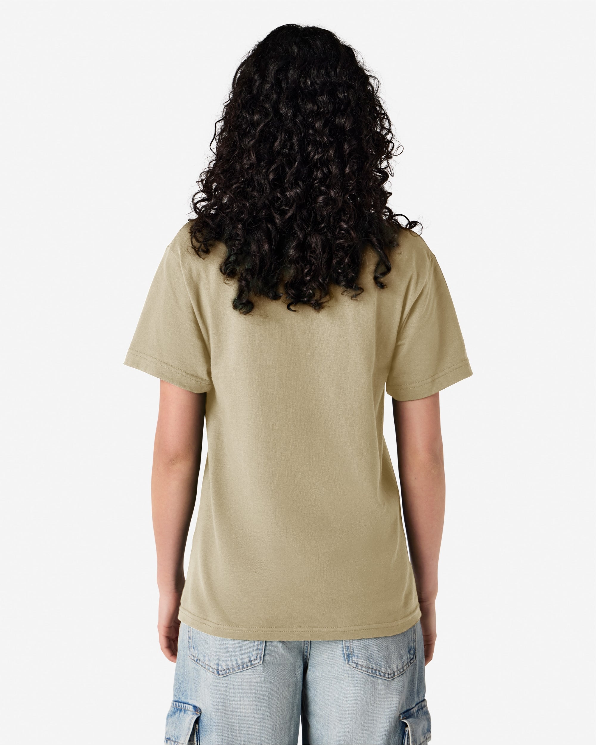 Female Model wearing a Sand Heavyweight Unisex Short Sleeve Crew Neck Tee, paired with blue jeans, standing against a plain background (back pose) -sand