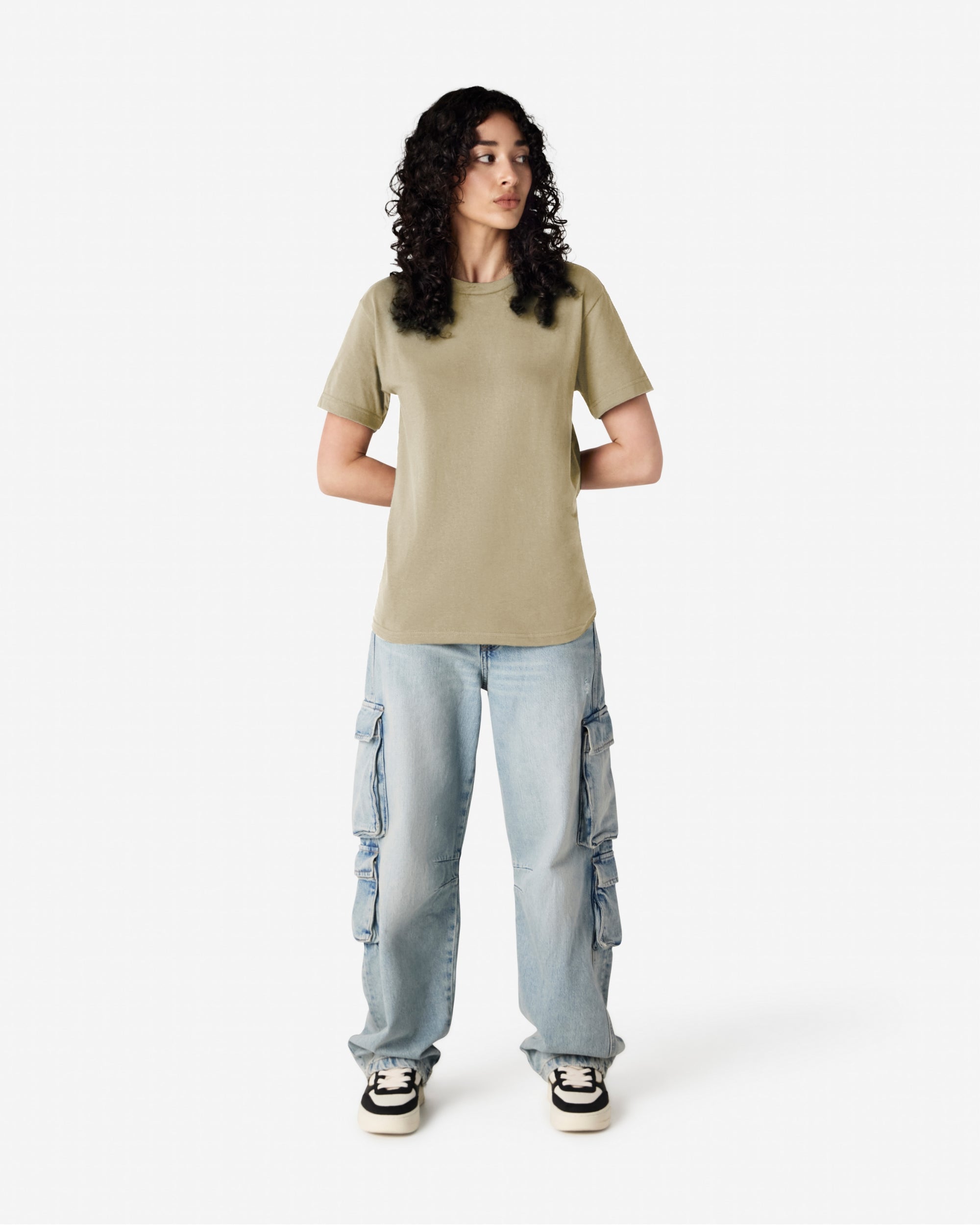 Female Model wearing a S Heavyweight Unisex Short Sleeve Crew Neck Tee, paired with blue jeans, standing against a plain background (front pose) -Sand