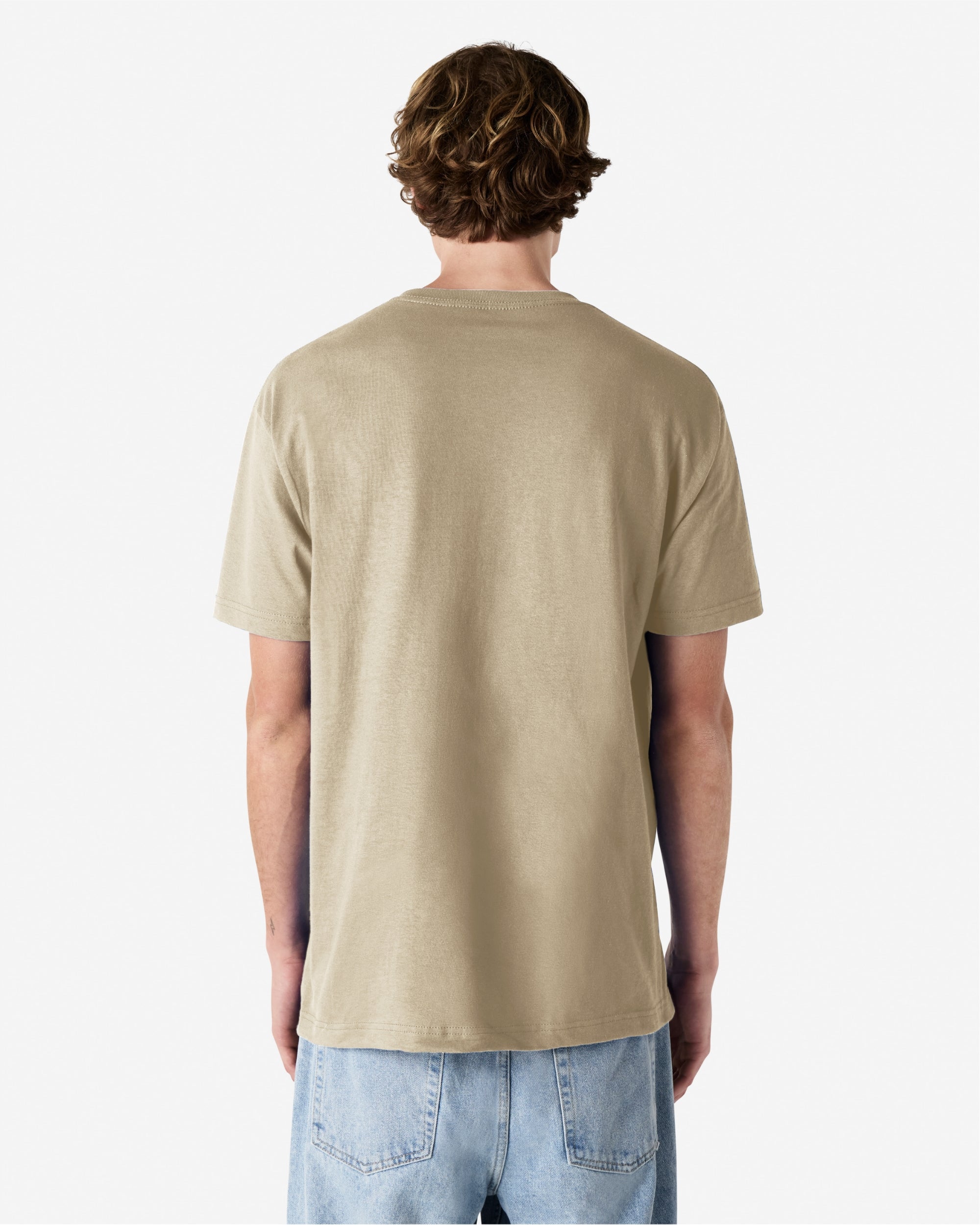 Male Model wearing a Sand Heavyweight Unisex Short Sleeve Crew Neck Tee, paired with blue jeans, standing against a plain background (back pose) -sand