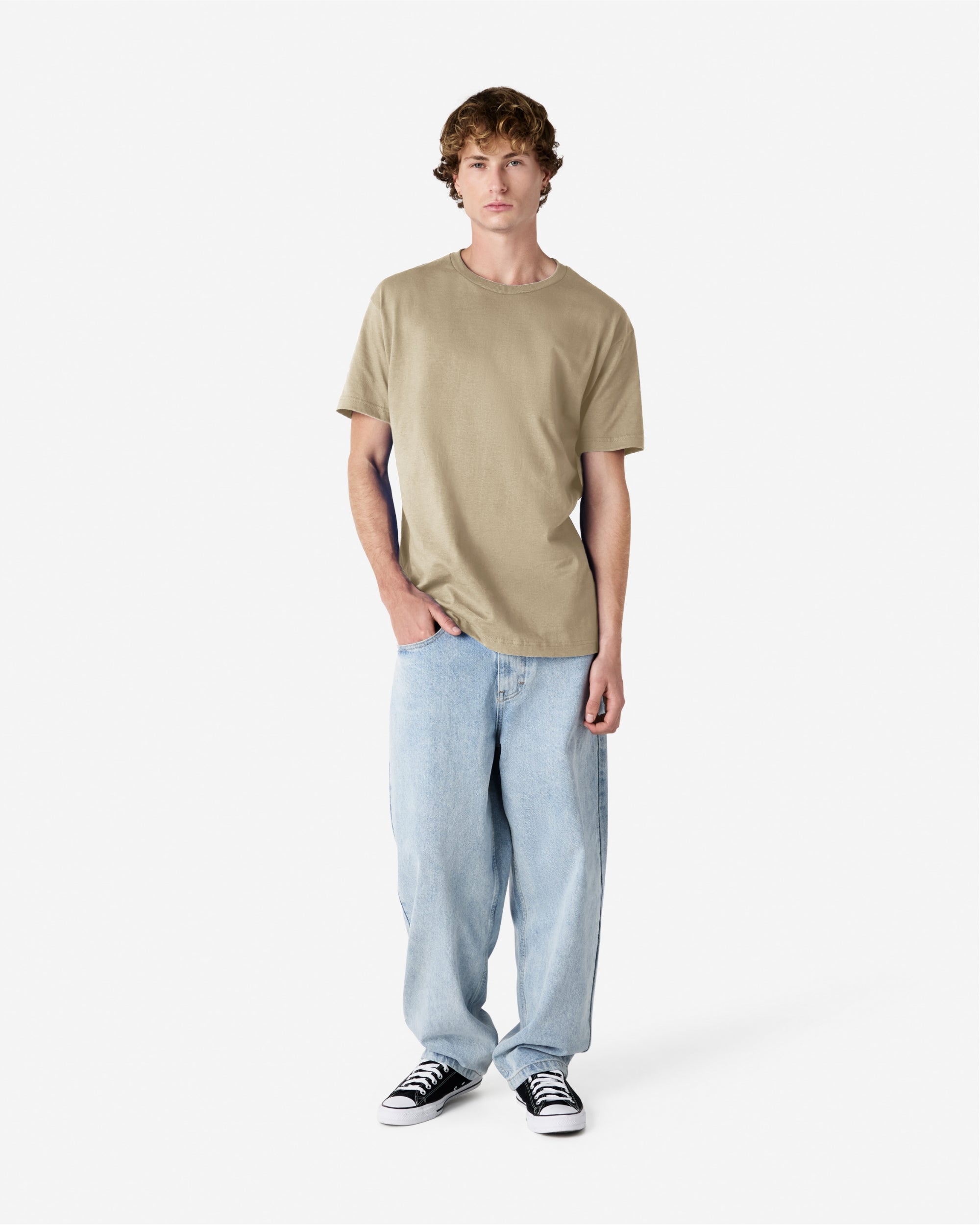 Male Model wearing a Sand Heavyweight Unisex Short Sleeve Crew Neck Tee, paired with blue jeans, standing against a plain background (front pose) -sand
