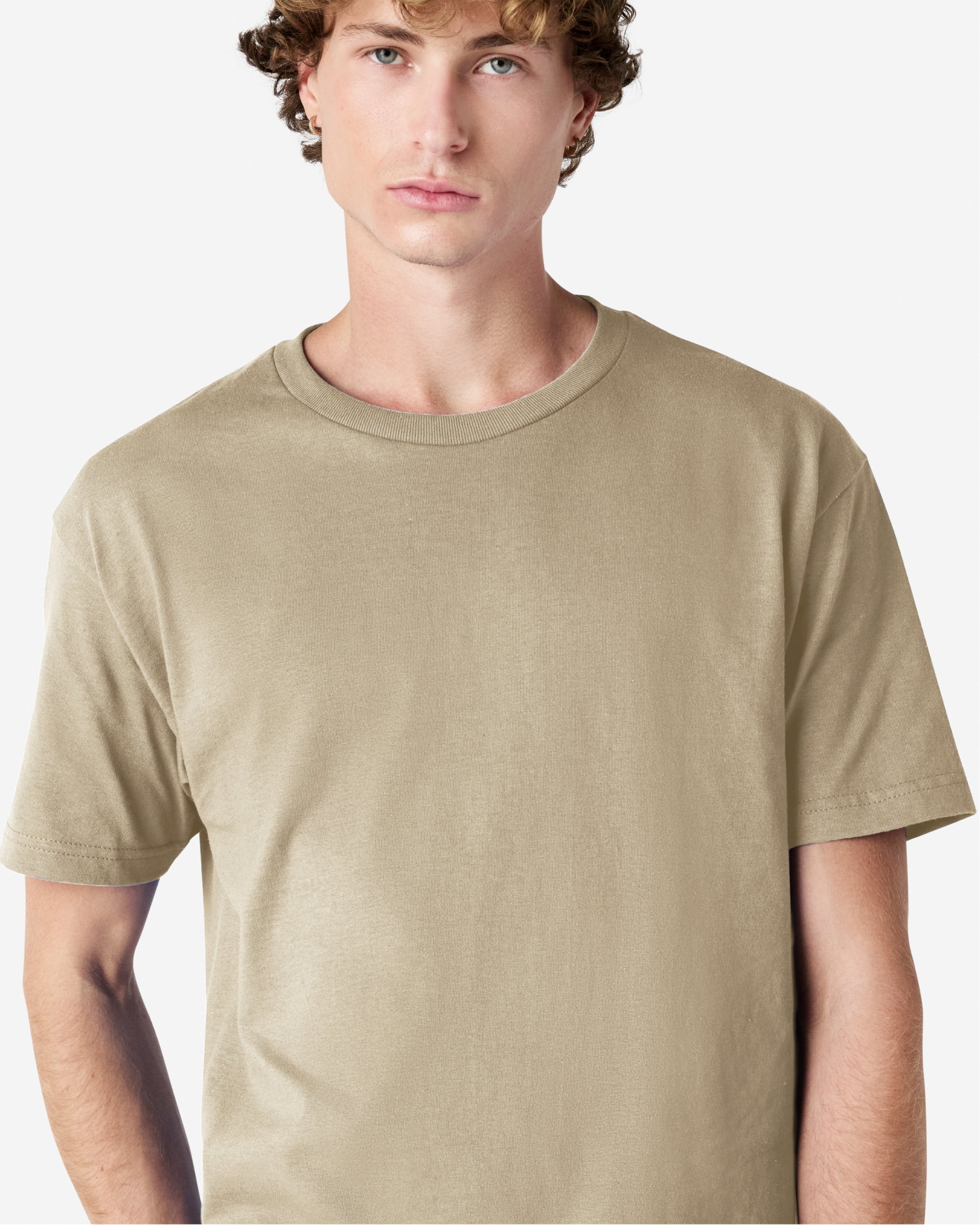 Male Model wearing a Sand Heavyweight Unisex Short Sleeve Crew Neck Tee, paired with blue jeans, standing against a plain background (front pose) -sand