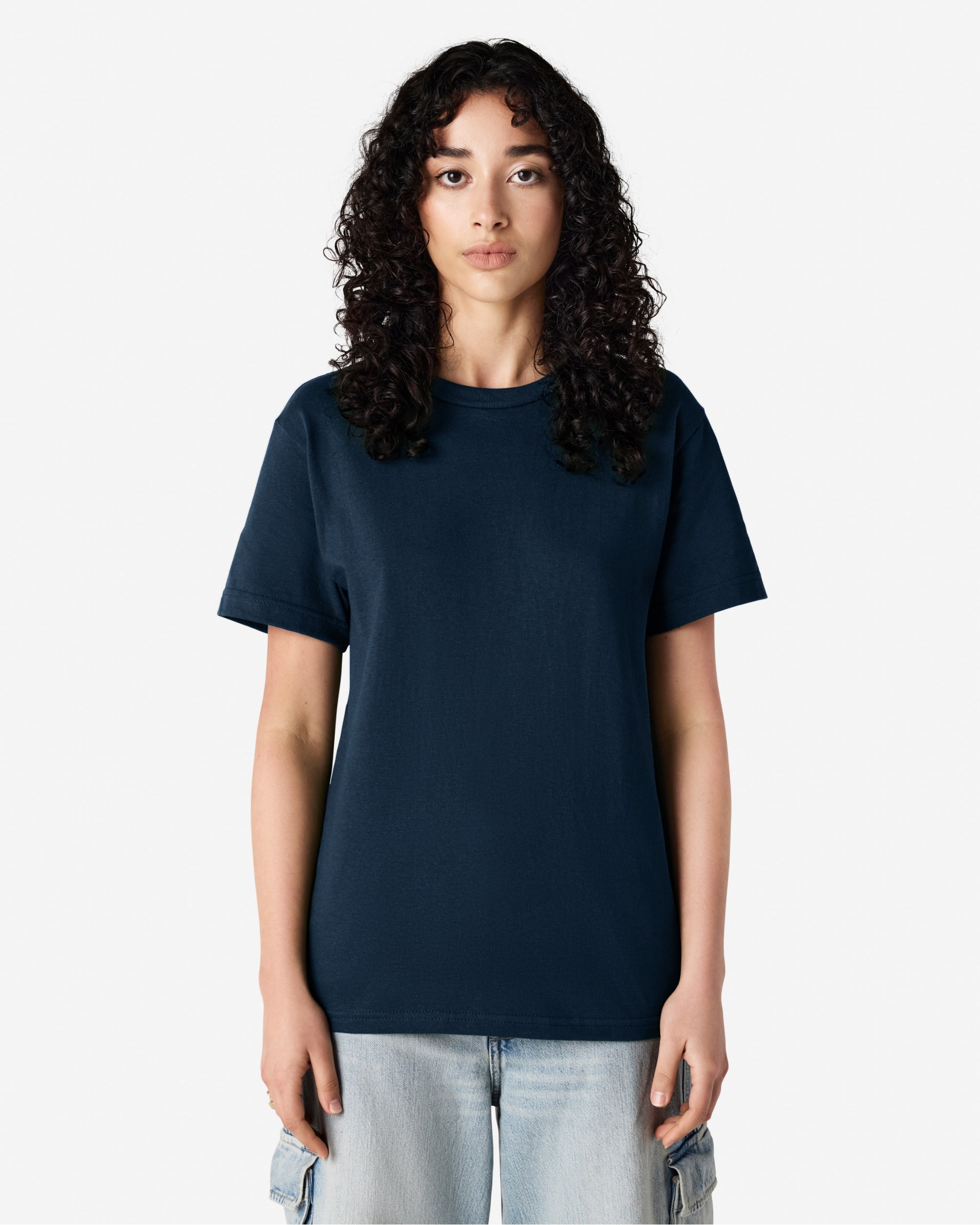 Female Model wearing a True Navy Heavyweight Unisex Short Sleeve Crew Neck Tee, paired with blue jeans, standing against a plain background (front pose) -true navy