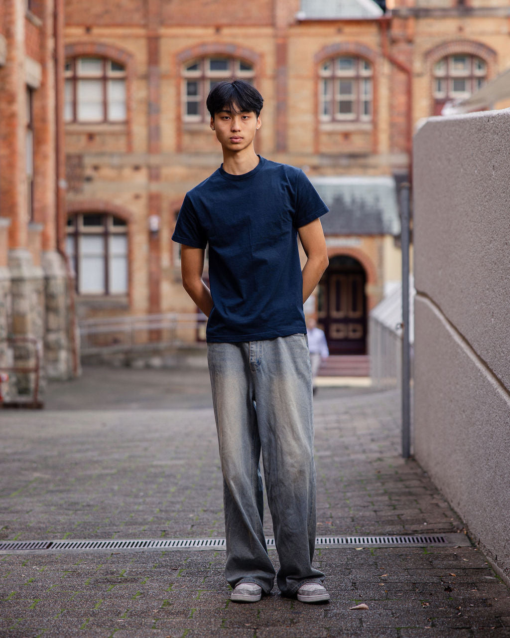 Male Model wearing a True Navy Heavyweight Unisex Short Sleeve Crew Neck Tee, paired with blue jeans, standing against a plain background (front pose) -true navy