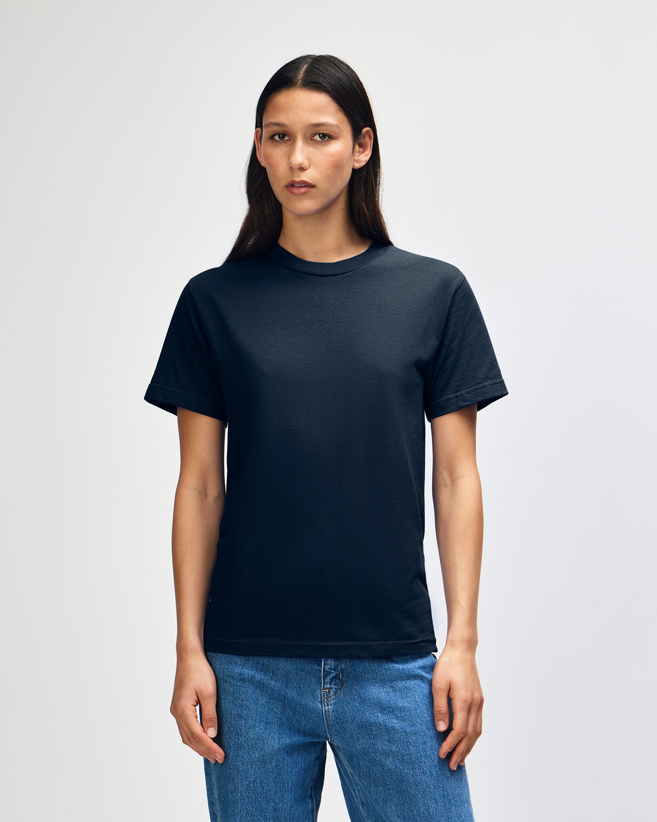 Female Model wearing a True Navy Heavyweight Unisex Short Sleeve Crew Neck Tee, paired with blue jeans, standing against a plain background (front pose) -true navy
