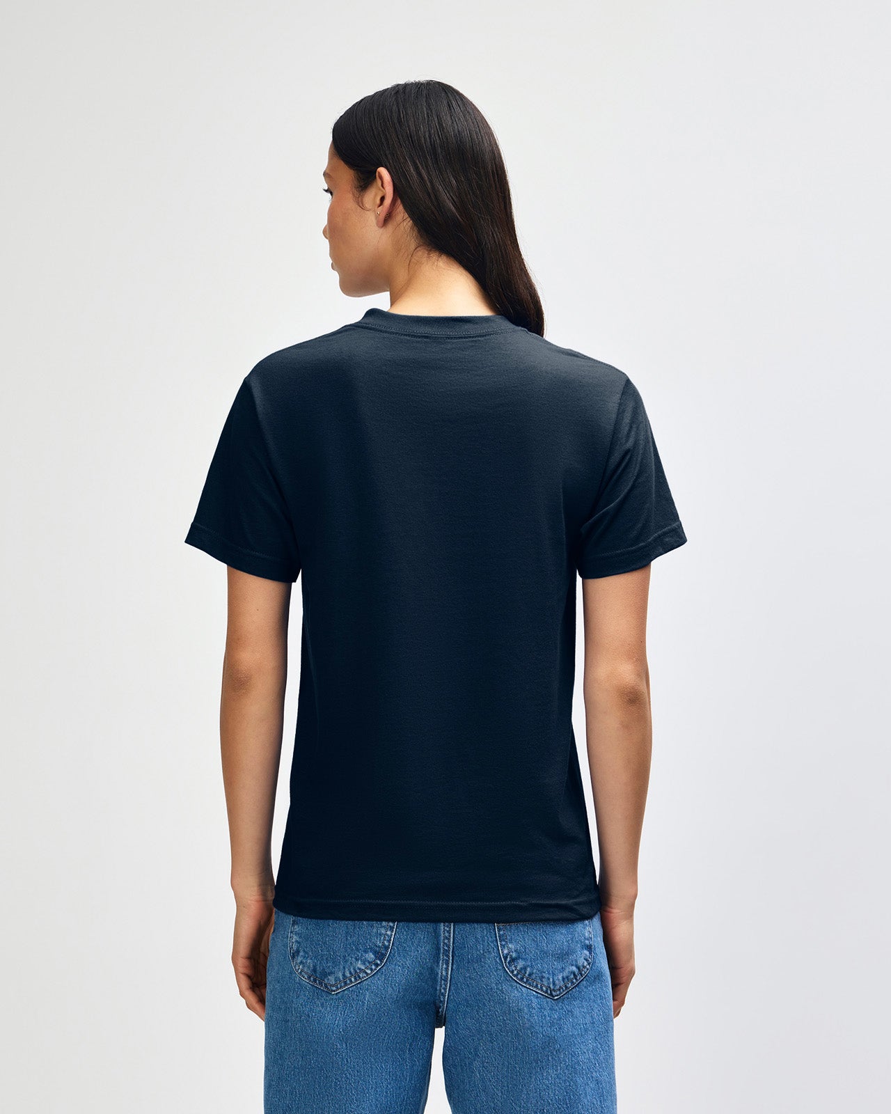 Female Model wearing a True Navy Heavyweight Unisex Short Sleeve Crew Neck Tee, paired with blue jeans, standing against a plain background (front pose) -true navy