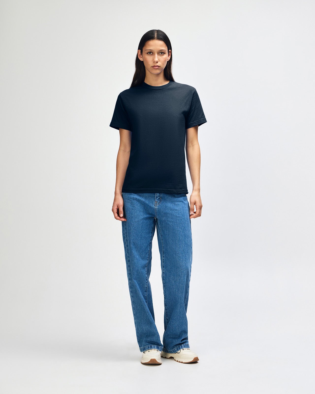 Female Model wearing a True Navy Heavyweight Unisex Short Sleeve Crew Neck Tee, paired with blue jeans, standing against a plain background (front pose) -true navy