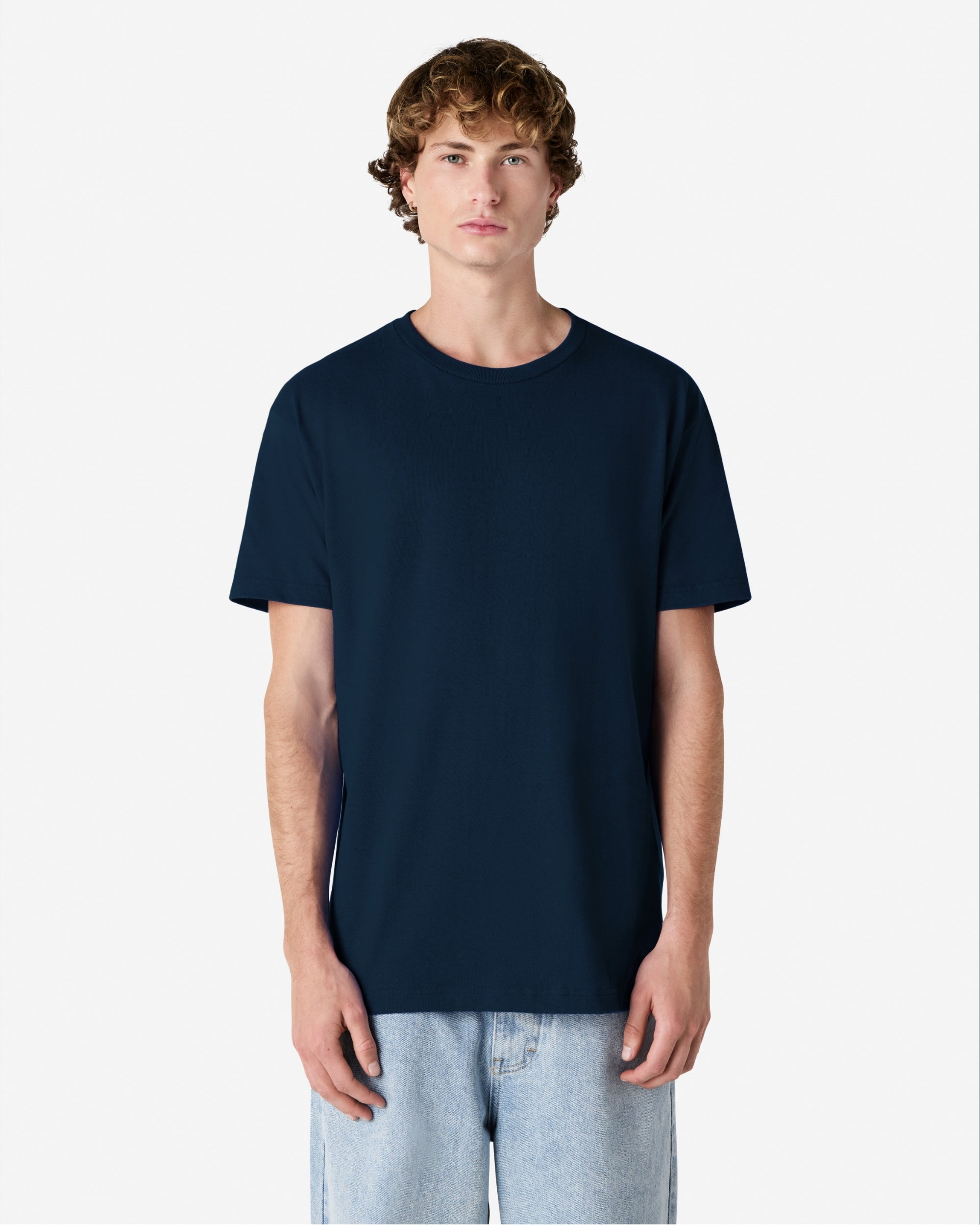 Male Model wearing a True Navy Heavyweight Unisex Short Sleeve Crew Neck Tee, paired with blue jeans, standing against a plain background (front pose) -true navy