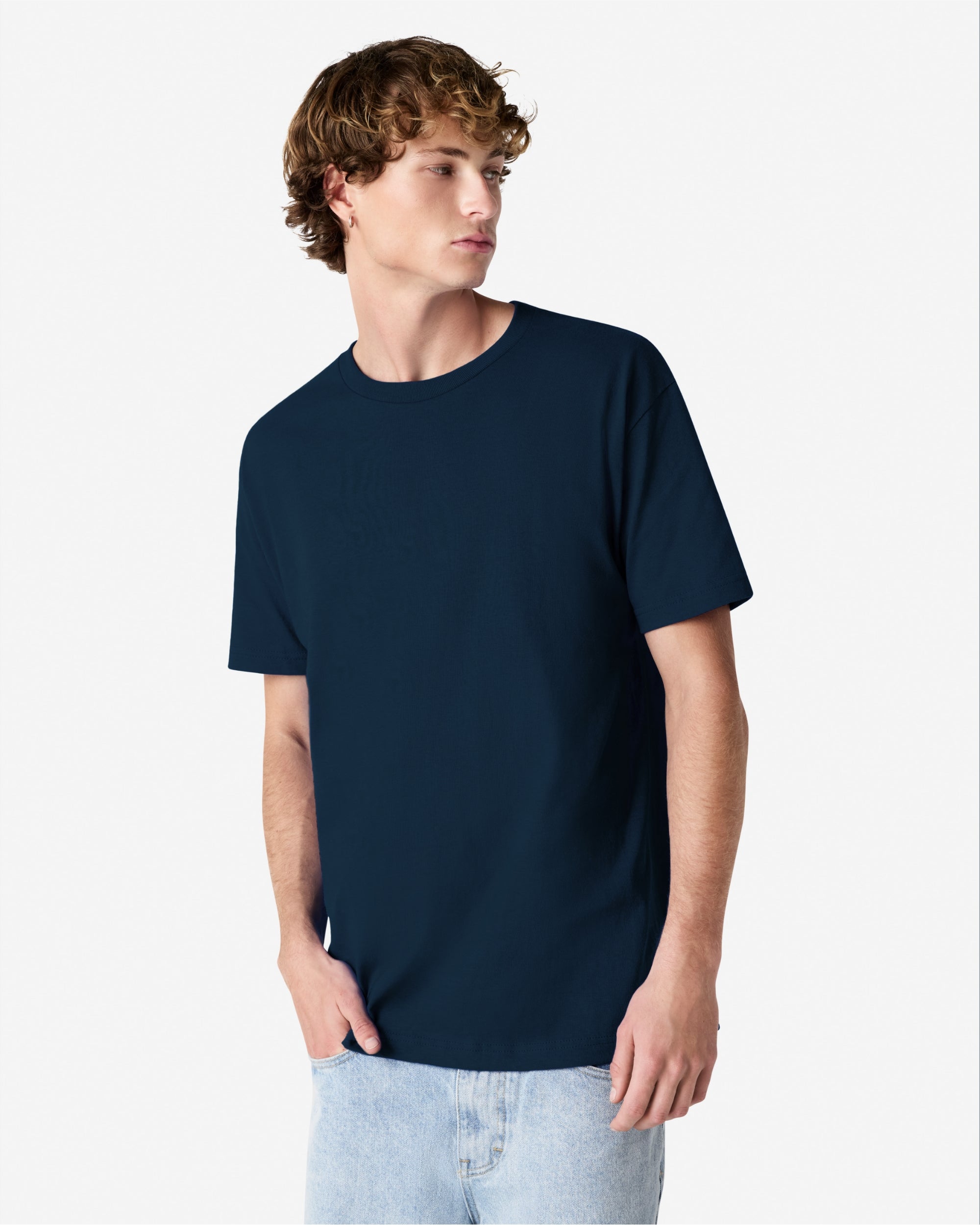 Male Model wearing a True Navy Heavyweight Unisex Short Sleeve Crew Neck Tee, paired with blue jeans, standing against a plain background (front pose) -true navy