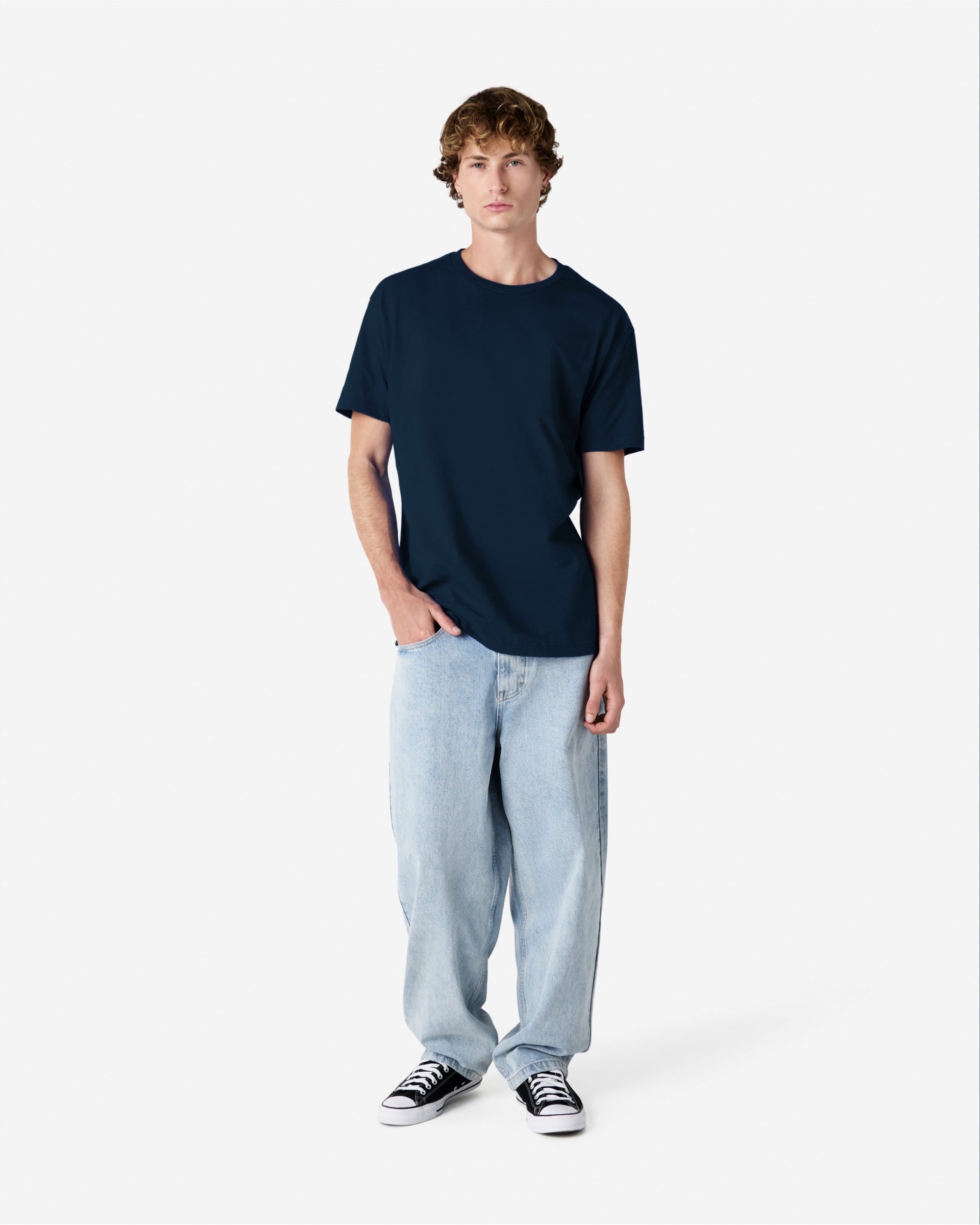 Male Model wearing a True Navy Heavyweight Unisex Short Sleeve Crew Neck Tee, paired with blue jeans, standing against a plain background (front pose) -true navy