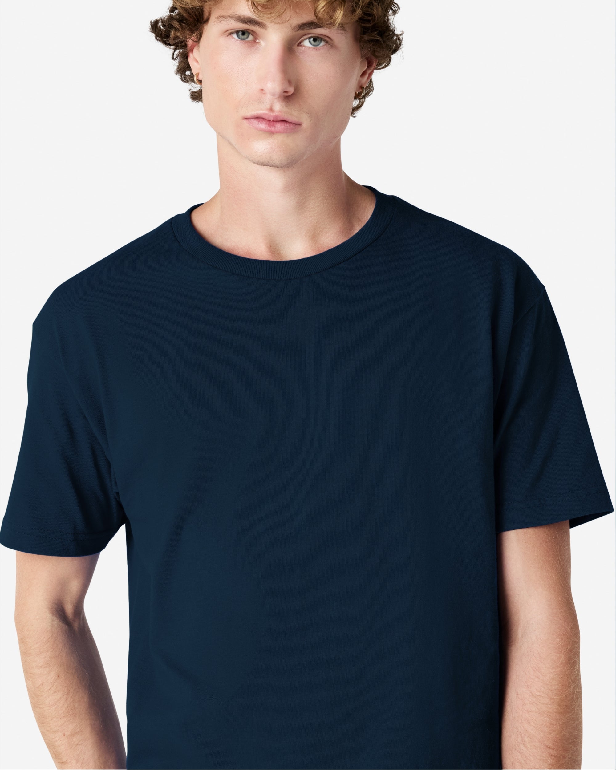 Male Model wearing a True Navy Heavyweight Unisex Short Sleeve Crew Neck Tee, paired with blue jeans, standing against a plain background (front pose) -true navy