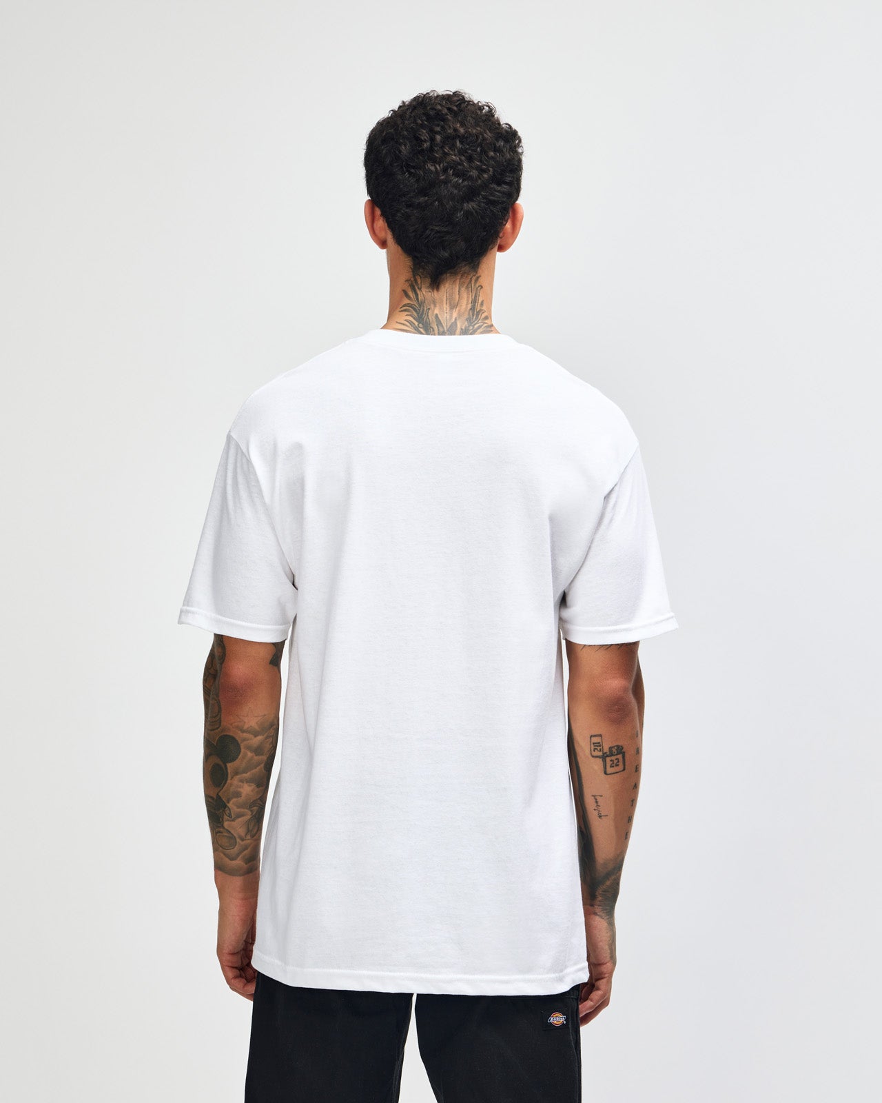 Male Model wearing a white Heavyweight Unisex Short Sleeve Crew Neck Tee, paired with blue jeans, standing against a plain background (front pose) -white