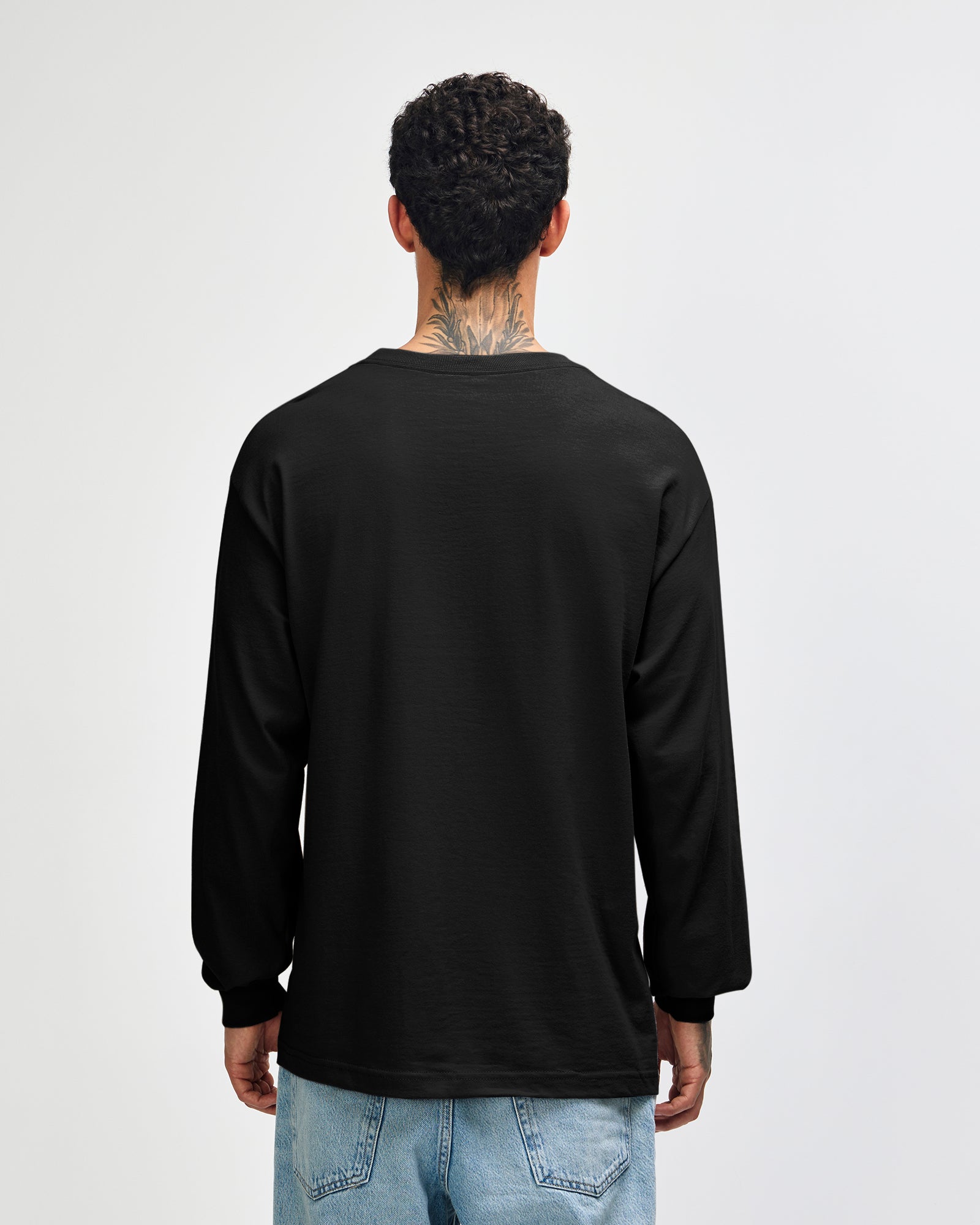 back view of a male Model wearing a black coloured Heavyweight Unisex Long Sleeve Crew Neck Tee, paired with blue jeans, standing against a plain background (back pose) -black