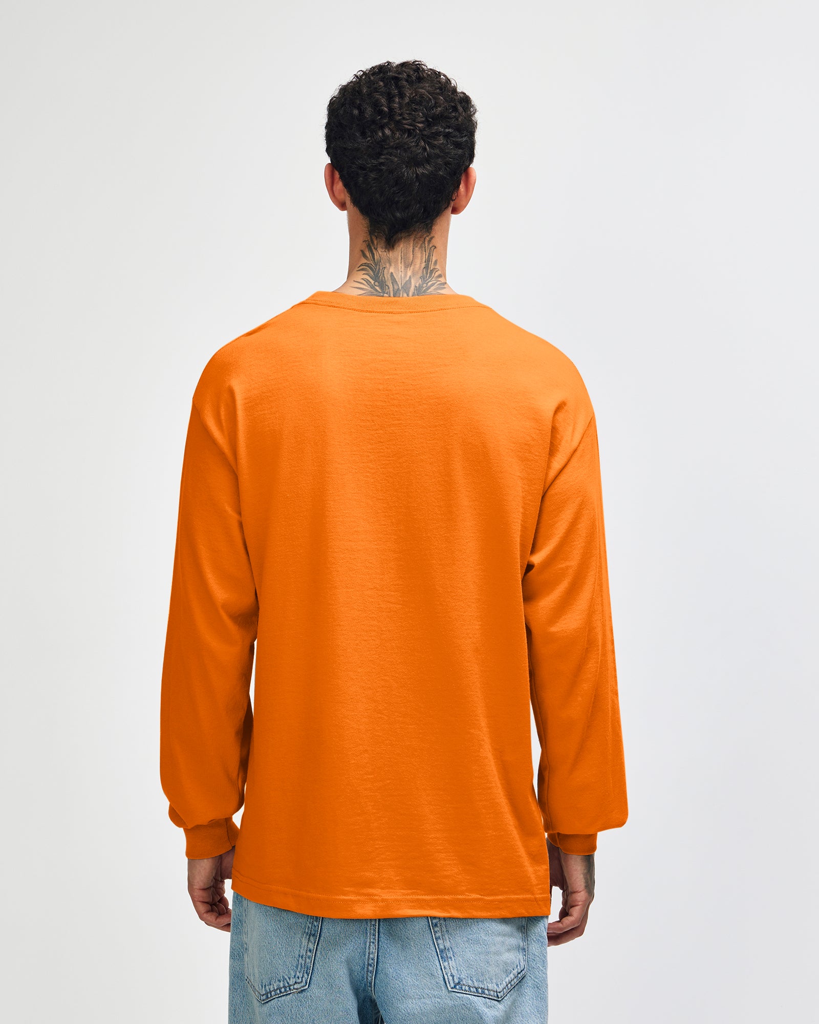 front view of a male Model wearing a Heather Orange Heavyweight Unisex Long Sleeve Crew Neck Tee, paired with blue jeans, standing against a plain background (front pose) -orange