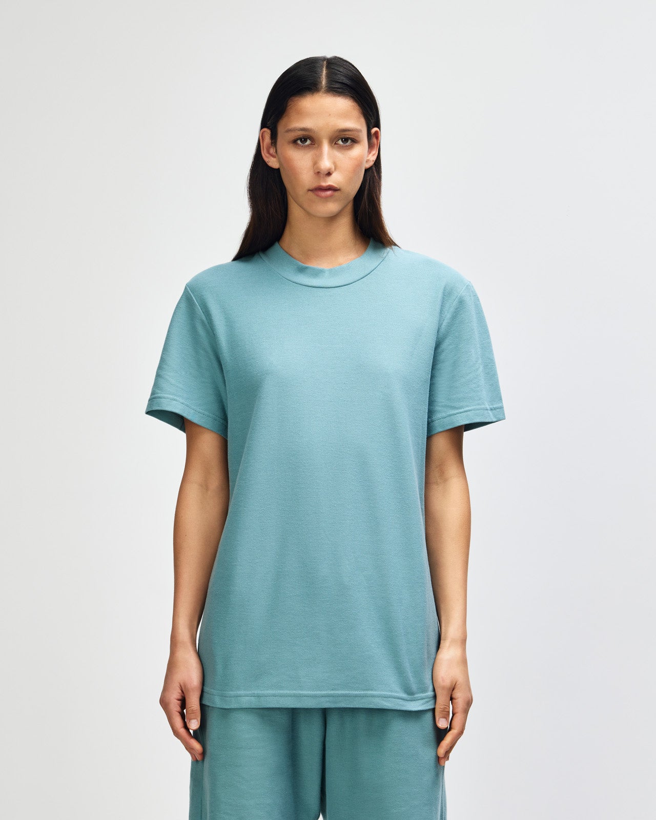 Female model wearing a Pique Unisex Mockneck Tee (front pose) -arctic