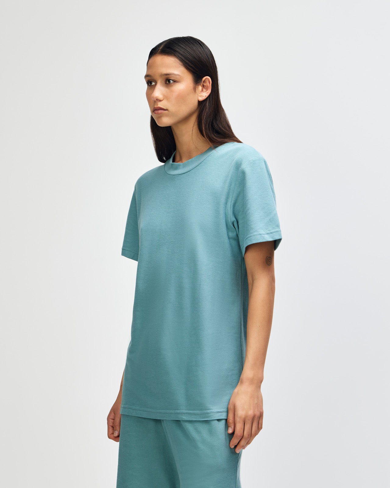 Female model wearing a Pique Unisex Mockneck Tee (front pose) -arctic