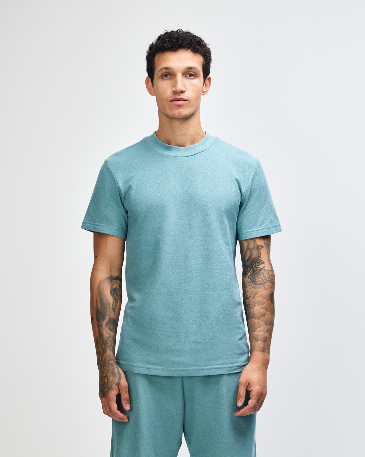 Male model wearing a Pique Unisex Mockneck Tee (front pose) -arctic