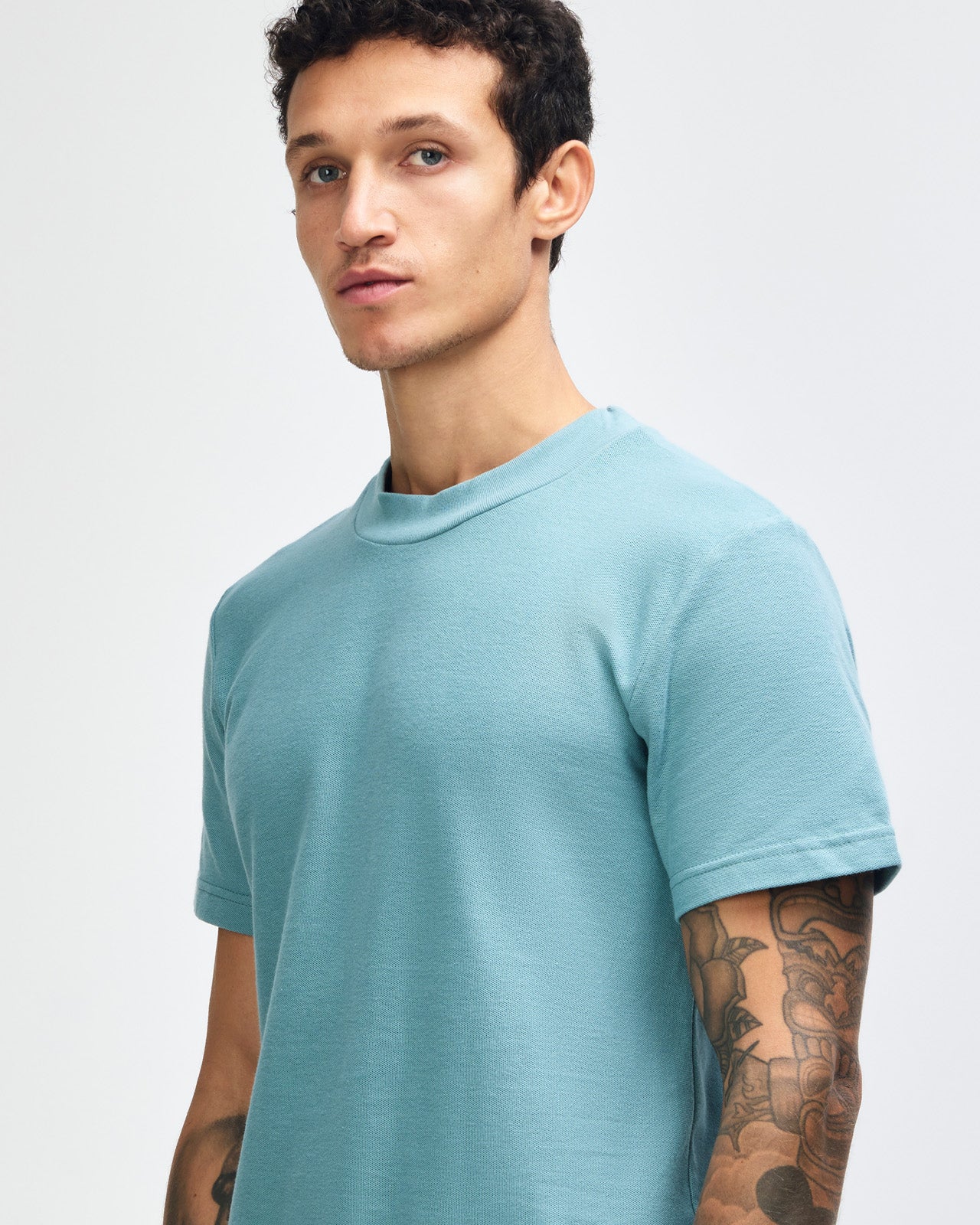 Male model wearing a Pique Unisex Mockneck Tee (front pose) -arctic