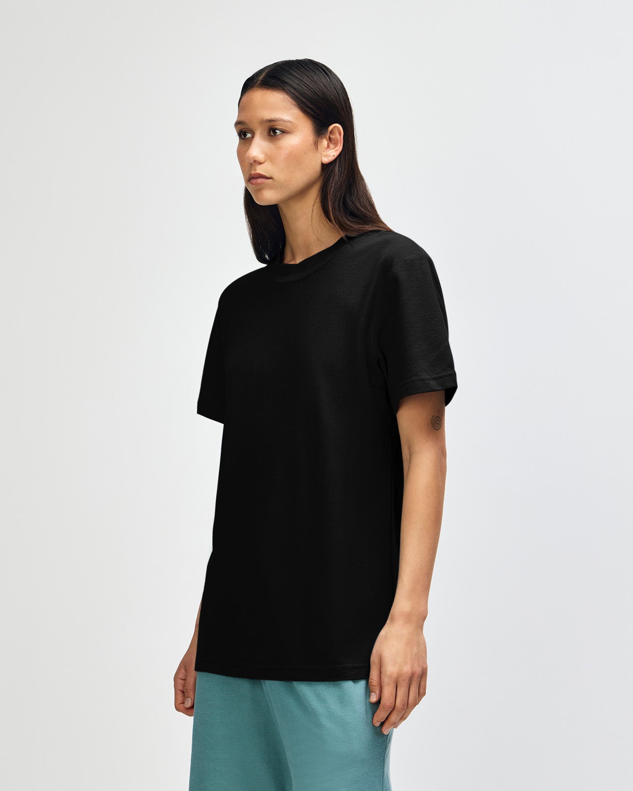 Female model wearing a Pique Unisex Mockneck Tee (front pose) -black