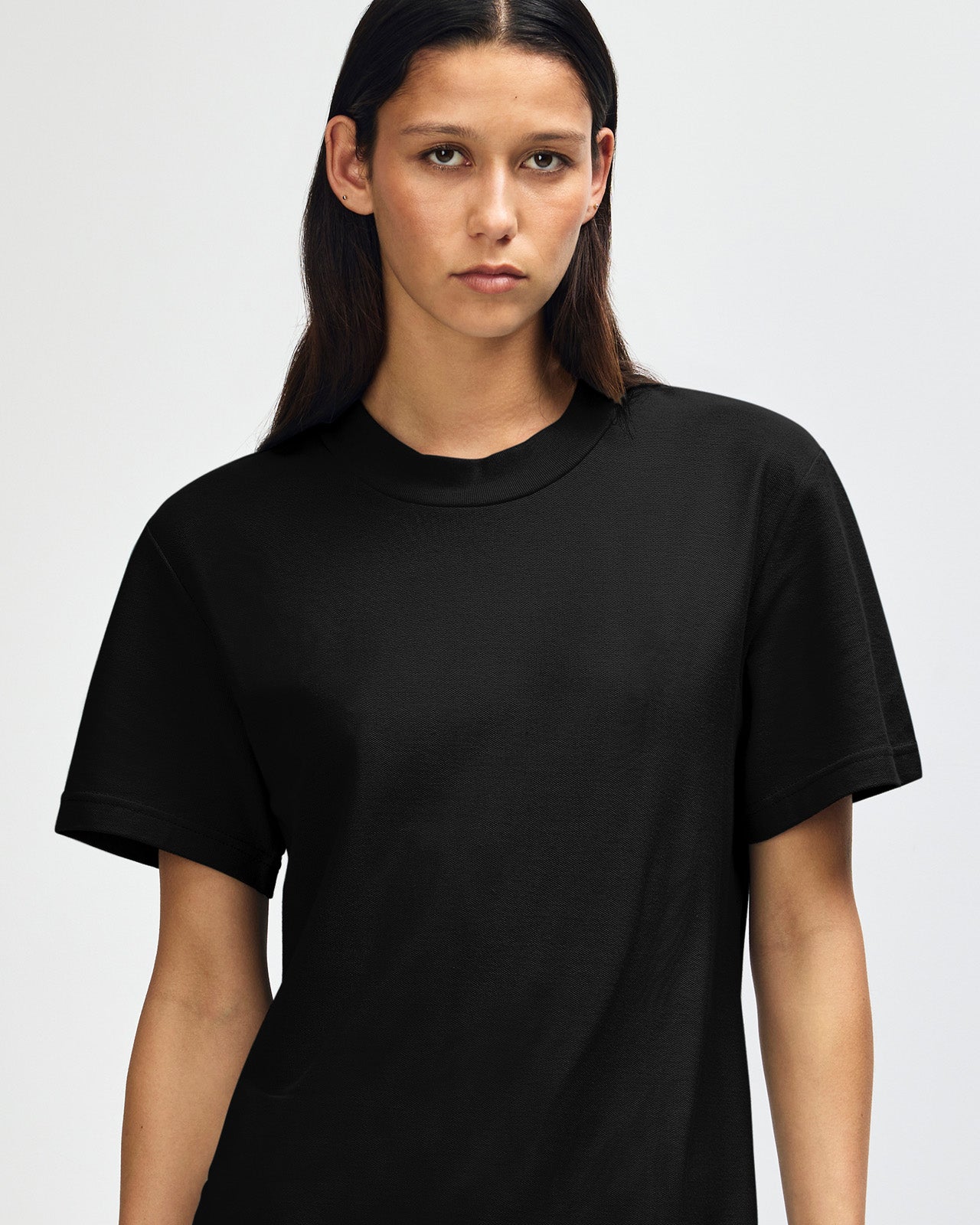 Female model wearing a Pique Unisex Mockneck Tee (front pose) -black
